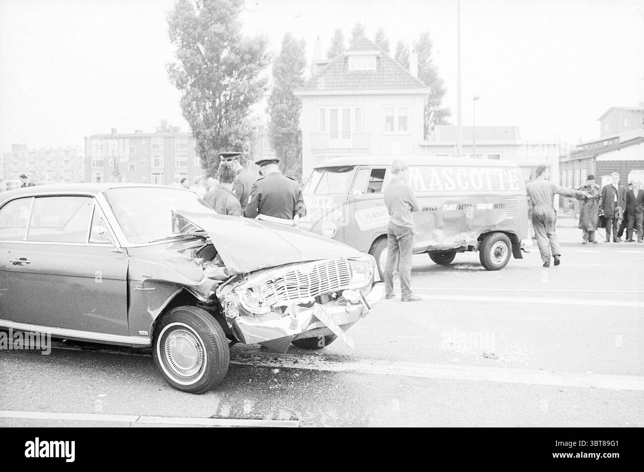Car Collision, Whizgle News, Dutch Desk, Niederlande, 1950 - 2000 am 06-08-1968. Die Abbildung zeigt diese Themen. Die Szene zeigt die Nachwirkungen eines Fahrzeugunfalls, wobei ein beschädigtes Auto mit einer zerknitterten Front sichtbar ist, was auf einen deutlichen Aufprall hinweist. Das Fahrzeug ist dunkel und verchromte Details glänzen trotz des umliegenden Chaos. In der Nähe steht ein offiziell aussehender Van, der möglicherweise zu einem Abschleppdienst oder einem Unternehmen gehört, mit dem Namen auf der Seite. Die Farbe des Lieferwagens ist leicht stummgeschaltet und fügt sich in den monochromatischen Ton der Szene ein. Eine Gruppe von Menschen versammelt sich Stockfoto