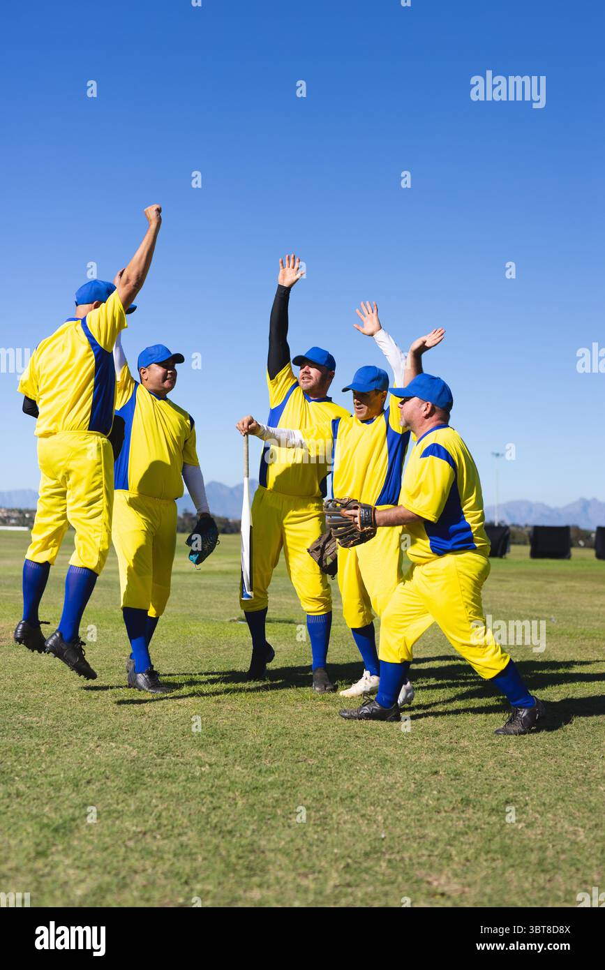 Sechs männliche Baseballspieler feiern auf dem Außenfeld mit Fledermaus und Handschuhen Stockfoto