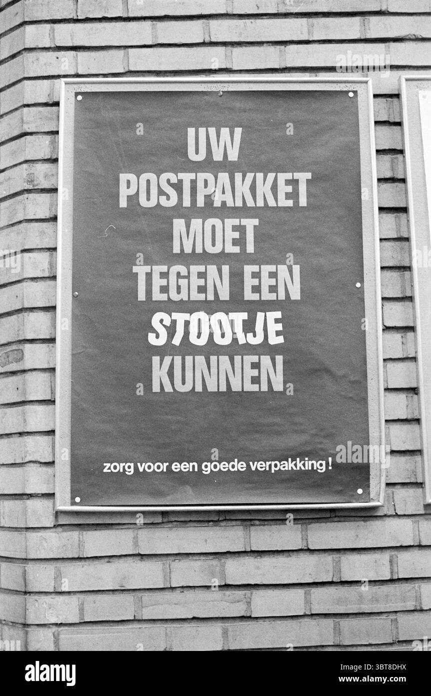 Schild für Postschilder, Whizgle News, Dutch Desk, Niederlande, 1950 - 2000 am 10-12-1970. Dies sind die Themen im Bild. Eine Backsteinmauer dient als Kulisse, deren raue Textur einen Eindruck von industriellem Charme verleiht. Die Beleuchtung ist weich und gedämpft, was auf einen bewölkten Tag hindeutet, der sanfte Schatten auf die Oberfläche wirft. In der Mitte der Szene befindet sich ein rechteckiges Schild mit fettgedrucktem Text, der sich deutlich vom gedämpften Hintergrund abhebt. Die Wörter sind visuell ansprechend angeordnet und betonen Schlüsselsätze mit unterschiedlichen Größen und Schriftarten. Die Farbpalette ist begrenzt, überwiegend fea Stockfoto