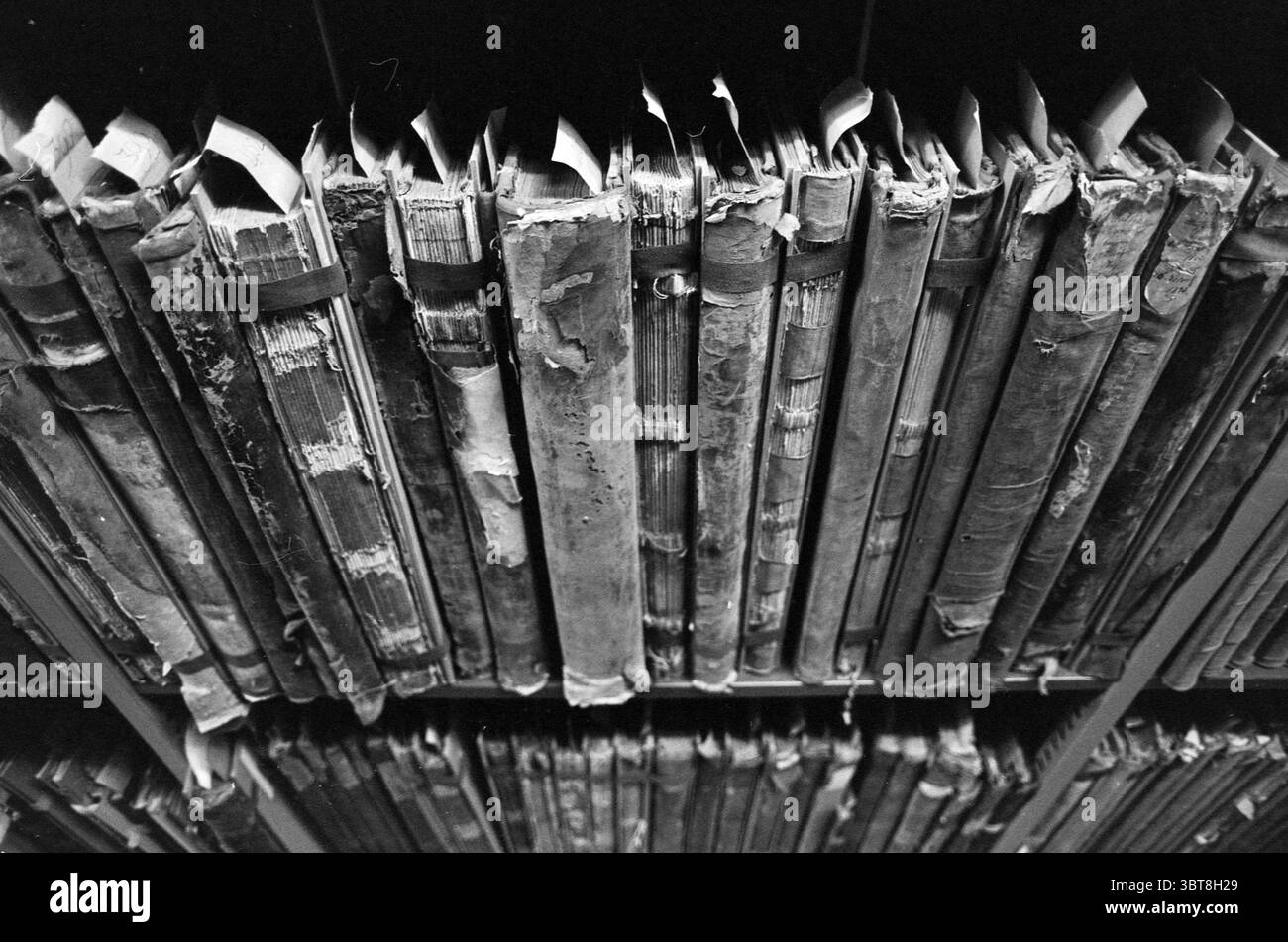 Staatsarchiv. Der Cultural Conservation Delta Plan gibt jedes Jahr Millionen für die Aufbewahrung der Archivdatei aus., Whizgle News, Dutch Desk, Niederlande, 1950 - 2000 am 16.11.1993. Das Bild enthält diese Themen. Die Szene zeigt eine Sammlung verwitterter Bände, die in Regalen angeordnet sind und ein Gefühl von Geschichte und Nostalgie vermitteln. Die Bücher sind in verblasste, dunkle Materialien gebunden, deren Rücken merklich abgenutzt und altert ist. Einige Kanten sind ausgefranst, andere zeigen Anzeichen für einen guten Daumen, was ihre lange Verwendung unterstreicht. Die gesamte Farbpalette wird von gedämpften Brauntönen und dominiert Stockfoto