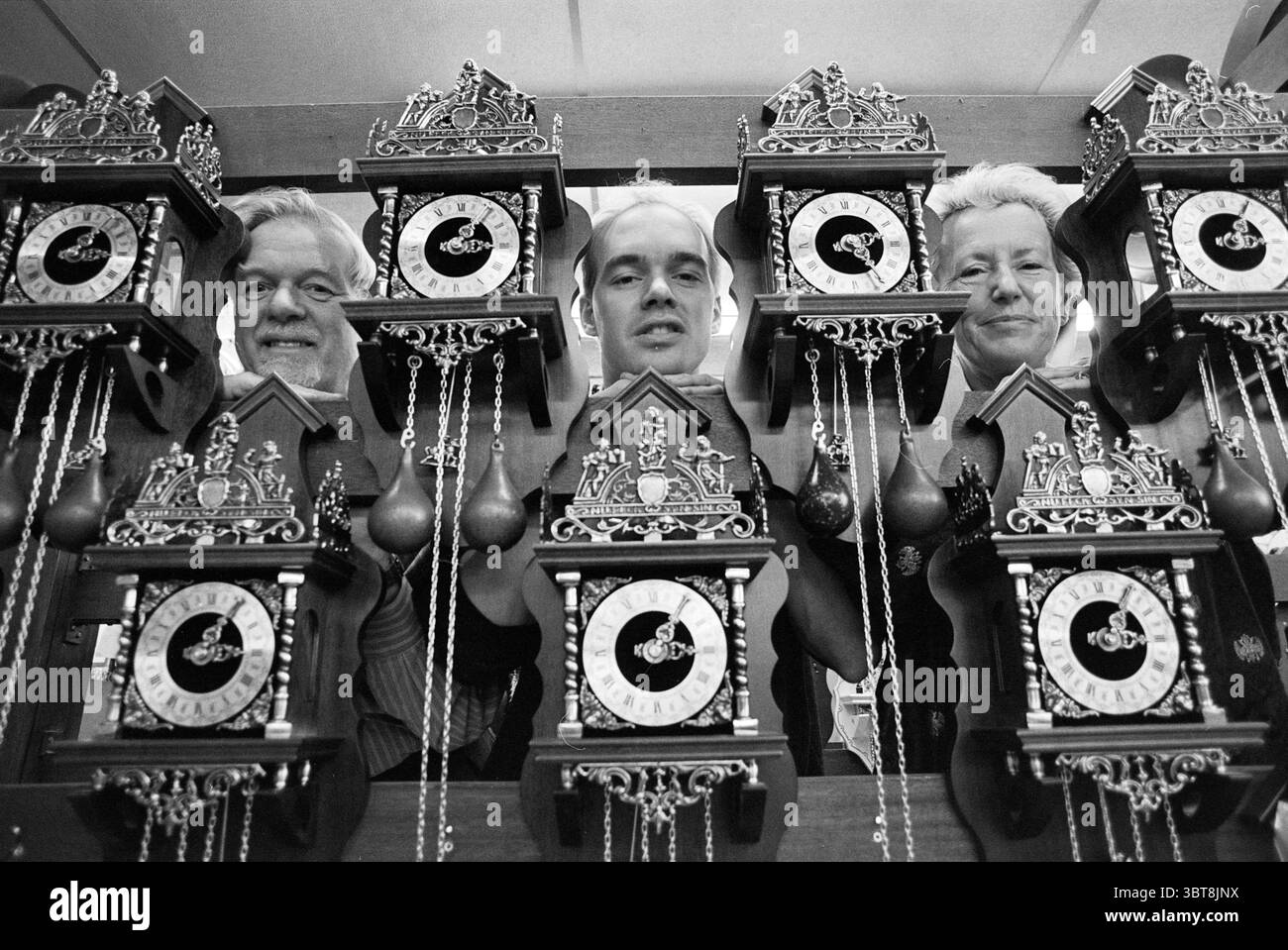 Alma Bells Hlem Haarlem Munterslaan the Netherlands, Whizgle News, Dutch Desk, Niederlande, 1950 - 2000 am 03-01-1995. Die Abbildung zeigt diese Themen. Die Szene zeigt drei Personen, die sich in einer Reihe von aufwändig gestalteten Uhren befinden. Jede Uhr zeigt kunstvolle Handwerkskunst mit detaillierten Schnitzereien und dekorativen Elementen, die eine reiche Palette an Holztönen, vergoldete Akzente und komplizierte Zifferblätter mit römischen Ziffern präsentieren. Die Individuen, zwei links und einer in der Mitte, zeigen Ausdrücke, die von Unbeschwertheit bis hin zu Konzentration reichen. Ihre Frisuren variieren, reflektieren Stockfoto