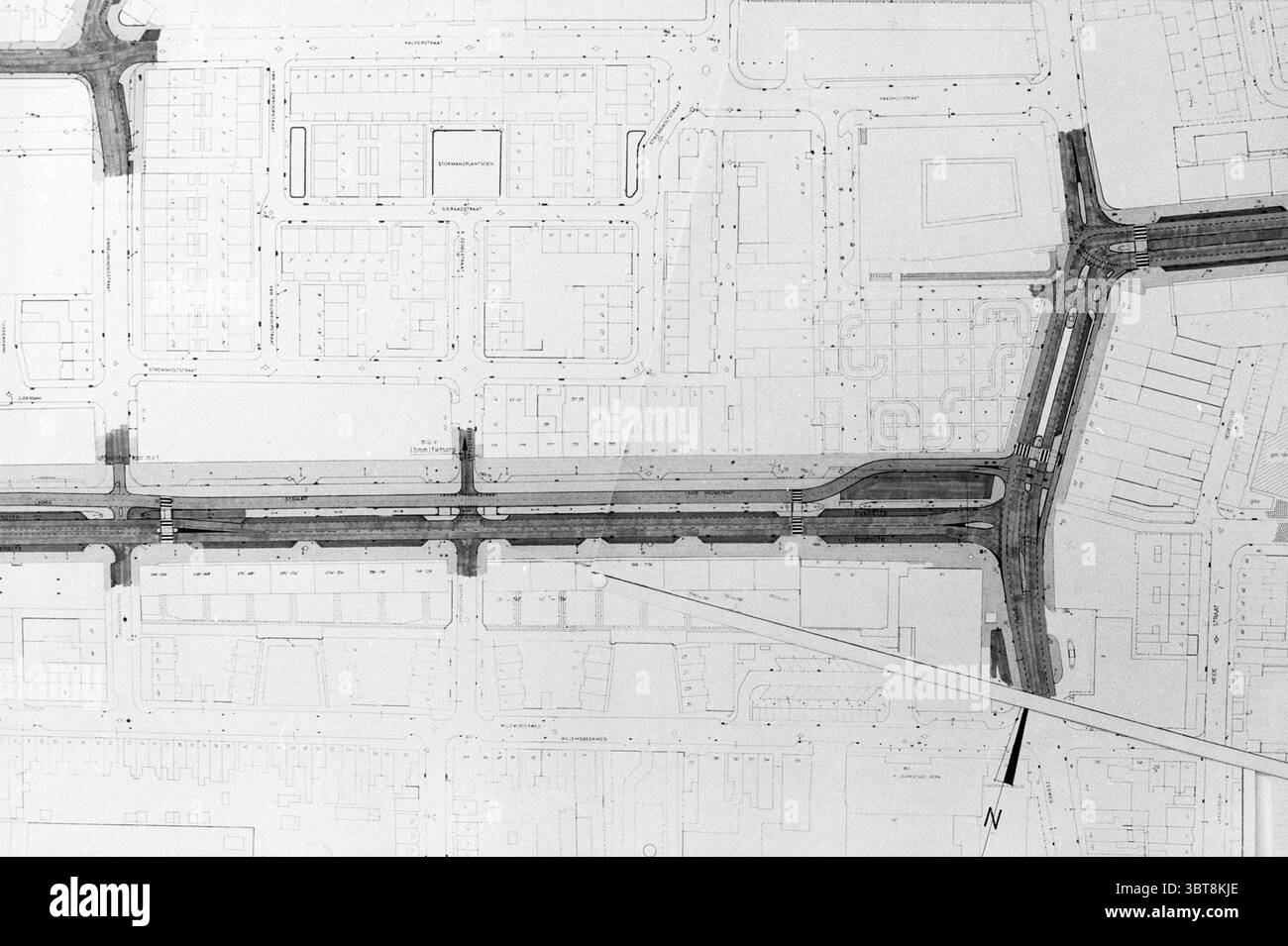 Zeichnung von Design Long Nieuwstraat IJmuiden Zeichnungen Zeichnungen IJmuiden lange Nieuwstraat Niederlande, Whizgle News, Dutch Desk, Niederlande, 1950 - 2000 am 27-04-1983. Die Abbildung zeigt diese Themen. Die Szene zeigt ein detailliertes Stadtbild, das einem Plan oder Stadtplan ähnelt. Straßen sind mit dünnen, dunklen Linien dargestellt, die ein Netzwerk bilden, das sich durch verschiedene rechteckige und quadratische Blöcke verschlingt. Einige Blöcke sind mit komplizierten Formen gefüllt, die auf Gebäude hinweisen, während andere größere Bereiche für offene Flächen oder Parks umfassen. Die Gesamtfarbpalette ist monochromatisch, unauffällig Stockfoto