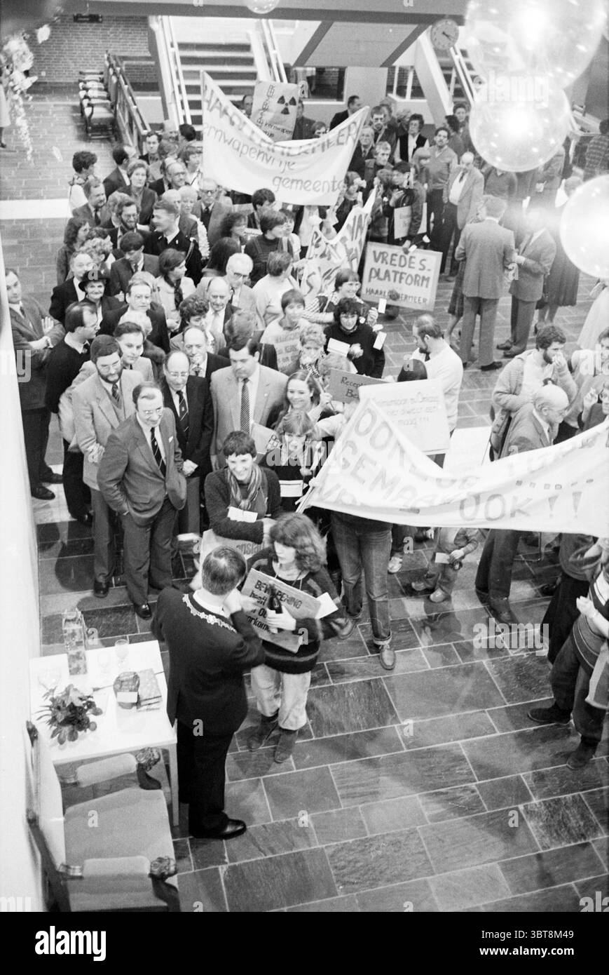 Installation Bürgermeister Hans de Boer von Haarlemmermeer im Rathaus Hoofddorp Raadhuisplein Niederlande, Whizgle News, Dutch Desk, Niederlande, 1950 - 2000 am 20-03-1983. Diese Themen werden in der Abbildung angezeigt. In einem belebten Innenbereich, der einem öffentlichen Versammlungsraum ähnelt, versammelt sich eine große Gruppe von Menschen, die eine Mischung aus engagierten und ernsten Ausdrücken demonstrieren. Die Menge ist dicht gepackt, mit Einzelpersonen, die Banner und Schilder hochhalten, die auf ein Thema des Protests oder Demonstrationen hinweisen. Die Farbpalette der Szene ist überwiegend monochrom und verleiht der Atmosphäre eine Vintage-Qualität Stockfoto