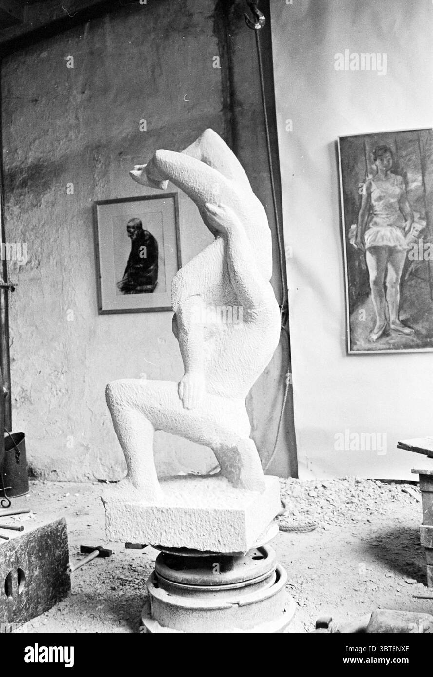 Skulptur von zwei Akrobaten im Atelier, die von einem Bildhauer bearbeitet werden, Whizgle News, Dutch Desk, Niederlande, 1950 - 2000. Die Abbildung zeigt diese Themen. In einem Atelierraum voller Kreativität und unvollendeter Kunstfertigkeit steht eine markante weiße Skulptur im Mittelpunkt. Die Skulptur selbst zeigt eine abstrakte Form einer Figur, die Elemente der menschlichen Anatomie mit einer unkonventionellen Pose verbindet. Zwei Arme scheinen um den Körper gewickelt zu sein, was auf ein Gefühl von Bewegung oder Spannung hindeutet, wobei sich die Gliedmaßen in die Gesamtstruktur eingliedern. Die Umgebung verfügt über eine strukturierte Wand, Stockfoto