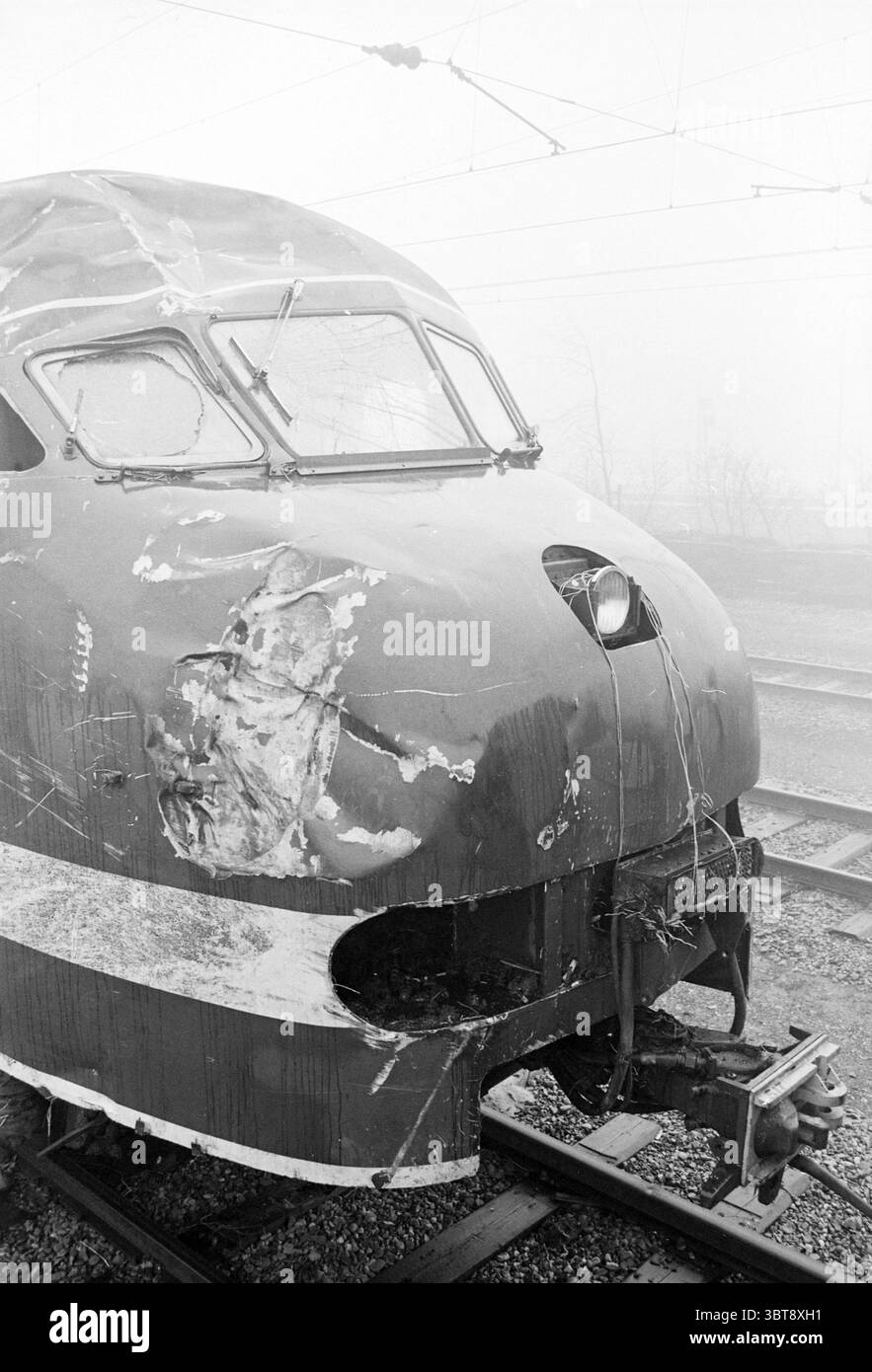 Schwer beschädigte Vorderseite des Zuges, der am 11. Februar 1966 in der Nähe von Halfweg entgleiste, Whizgle News, Dutch Desk, Niederlande, 1950 - 2000 am 11. November 1966. Die Abbildung zeigt diese Themen. Die Szene zeigt eine Nahaufnahme der Bahnfront, die sich durch ein klassisches, stromlinienförmiges Design auszeichnet. Das Äußere ist in einem verblassten Rot lackiert, wobei Abschnitte Anzeichen von Verschleiß und Beschädigung zeigen, einschließlich Kratzern und Dellen, die darauf hindeuten, dass es bessere Tage erlebt hat. Die Nase des Zuges ist abgerundet und verleiht ihm einen futuristischen Look für seine Zeit. Die großen, markanten Fenster sind leicht konvex und ermöglichen einen Blick Stockfoto