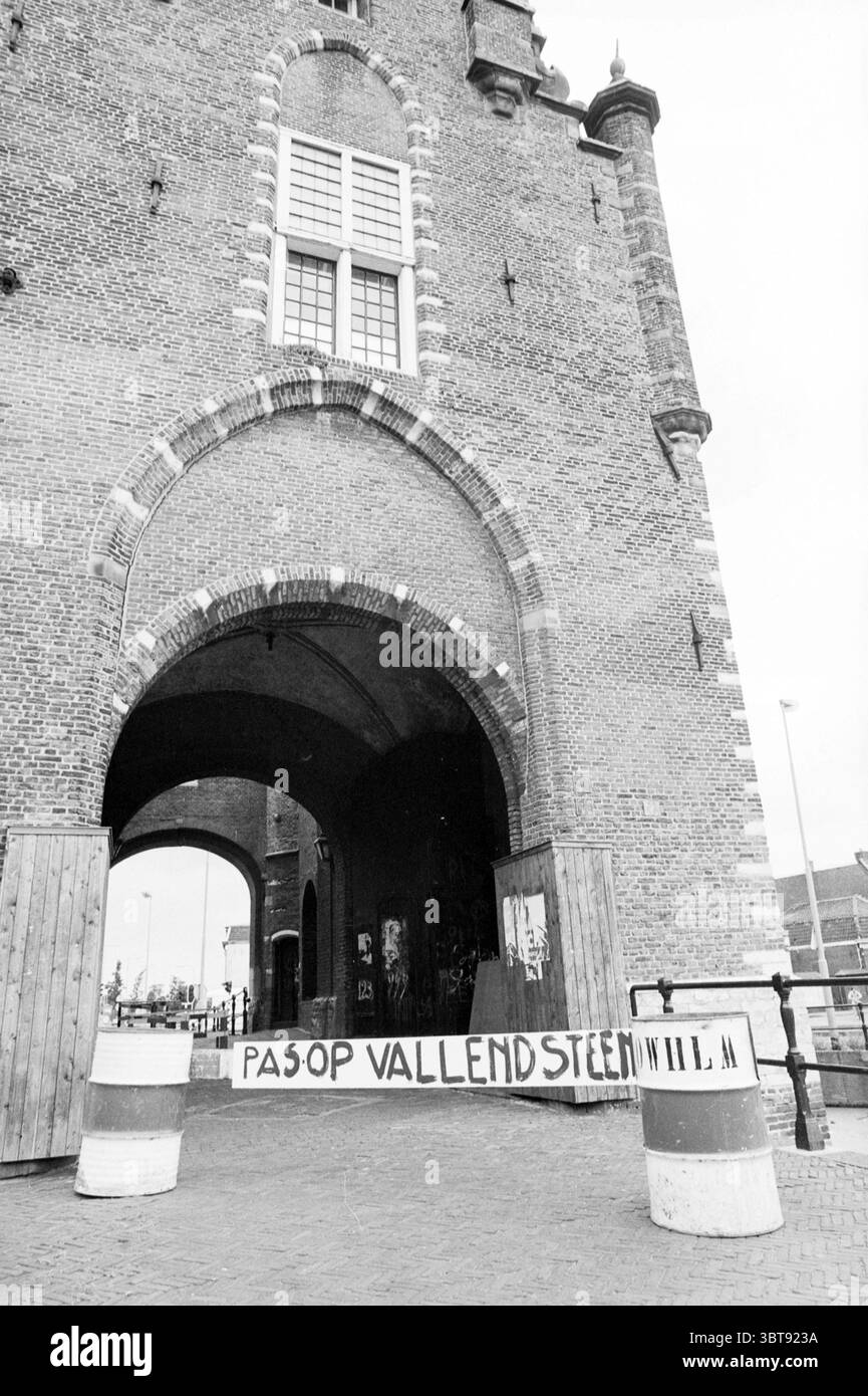 Renovierung Amsterdamse Poort + Schild Renovierung Haarlem the Netherlands, Whizgle News, Dutch Desk, Niederlande, 1950 - 2000 am 18-06-1981. Diese Themen werden in der Abbildung angezeigt. Die Szene präsentiert eine historische Backsteinstruktur, die für ihre beeindruckende Größe und architektonische Details bekannt ist. Das Mauerwerk zeigt eine warme, aber gedämpfte Farbpalette, hauptsächlich in Braun und Rot, wobei einige Bereiche in Grau verfallen. Der Eingang verfügt über einen großen Torbogen, flankiert von großen, verwitterten Holztüren, die auf eine geschichtsträchtige Vergangenheit hinweisen. Oberhalb des Bogens lassen hohe, schmale Fenster einen Blick auf das Innere werfen, eingerahmt von Intr Stockfoto