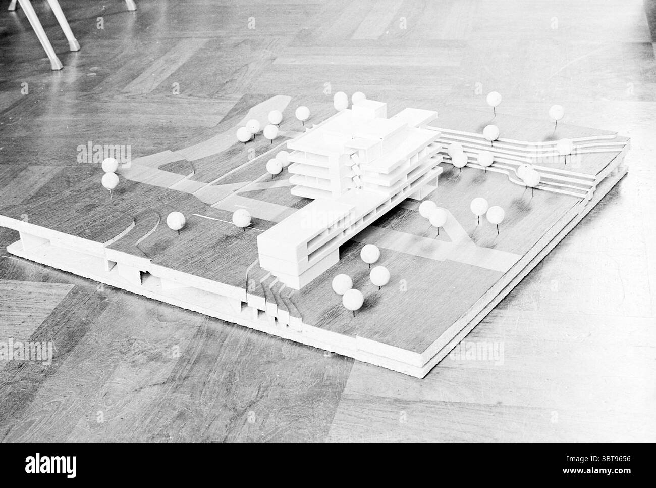 Model Noordwijk Town Hall Model, Whizgle News, Dutch Desk, Niederlande, 1950 - 2000 am 24-10-1967. Das Bild enthält diese Themen. Die Szene zeigt ein maßstabsgetreues Modell eines modernen architektonischen Designs auf einer flachen, hölzernen Oberfläche. Das Modell besteht aus mehreren sich überschneidenden rechteckigen Strukturen, die klare Linien und eine minimalistische Ästhetik aufweisen. Diese Strukturen sind aus hellem Material gefertigt und verleihen ihnen ein gestochen scharfes, weißes Aussehen. Um die Gebäude herum befinden sich mehrere kleine kugelförmige Darstellungen von Bäumen oder Sträuchern, die gleichmäßig über die Basis verteilt sind Stockfoto