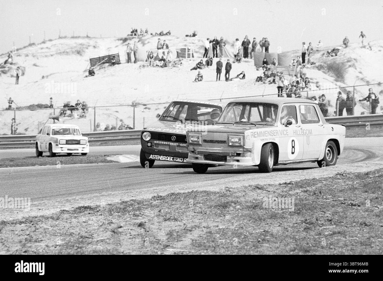 Verschiedene Rennen auf der Strecke in Zandvoort, Whizgle News, Dutch Desk, Niederlande, 1950 - 2000 am 04.-1981. Diese Themen werden in der Abbildung angezeigt. Die Szene fängt einen aufregenden Moment bei einem Motorsport-Event ein, bei dem mehrere Oldtimer auf einer kurvenreichen Strecke fahren. Im Vordergrund stehen zwei Autos in engem Wettbewerb, eines davon ist ein hell lackiertes Fahrzeug, möglicherweise weiß, mit Rennaufklebern verziert. Es scheint sich in einer engen Kurve zu befinden und zeigt die Dynamik von Geschwindigkeit und Präzision. Das andere Fahrzeug ist dunkler und zeichnet sich durch eine schlanke Silhouette aus, die einen starken Kontrast zum leichteren Fahrzeug bildet. Der Backg Stockfoto