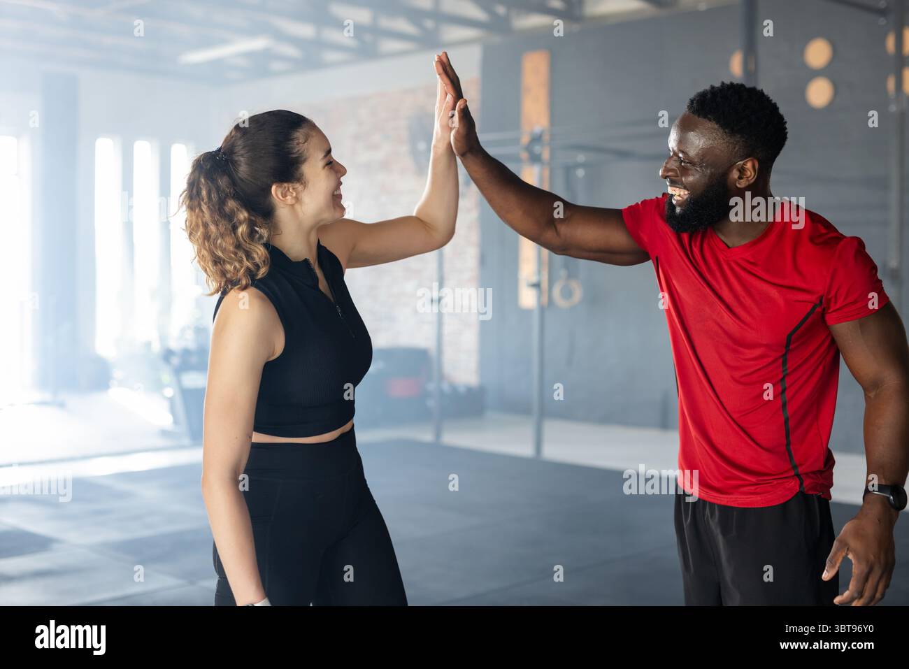 Verschiedene Freunde stehen auf Matten im Fitnessstudio mit Klimmzugstangen und Ringen Stockfoto