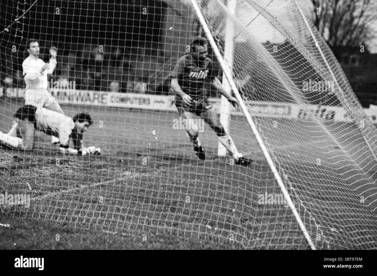 Haarlem - Fortuna SC Football Haarlem, Whizgle News, Dutch Desk, Niederlande, 1950 - 2000 am 10-11-1988. Das Bild enthält diese Themen. Die Szene fängt einen dynamischen Moment auf einem Fußballfeld vor dem Hintergrund des bewölkten, bewölkten Himmels ein. Die vorherrschenden Farben sind stumm geschaltet, was die monochrome Ästhetik der Umgebung widerspiegelt. Im Vordergrund stehen zwei Spieler im Mittelpunkt des Geschehens. Ein Spieler, der ein dunkles Trikot trägt, befindet sich in einer Sprintposition, während er sich dem Tor nähert und Entschlossenheit und Dringlichkeit ausstrahlt. Seine Haltung deutet darauf hin, dass er entweder den Ball schlagen oder einem Gegner ausweichen will. H Stockfoto