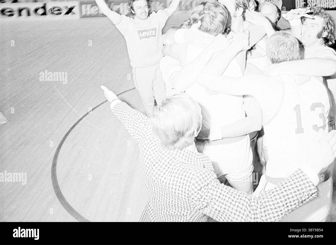 Basketballspiel Levi's gegen Fiat und Zeremonie in Ahoy Rotterdam., Whizgle News, Dutch Desk, Niederlande, 1950 - 2000. Dies sind die Themen im Bild. In einer belebten Halle entfaltet sich eine triumphale Szene, während eine Gruppe von Athleten in passenden Uniformen einen siegreichen Moment feiert. Das Basketballfeld leuchtet unter hellen Deckenlichtern und betont den polierten Holzboden und die leuchtenden Farben der Spieleroutfits. Eine Gruppe von Athleten, die sichtbar belebt sind, sind eng zusammengepackt und teilen fröhliche Umarmungen und Lachen. Ihre Gesichter strahlen eine Mischung aus Spannung und Vertrauen aus Stockfoto