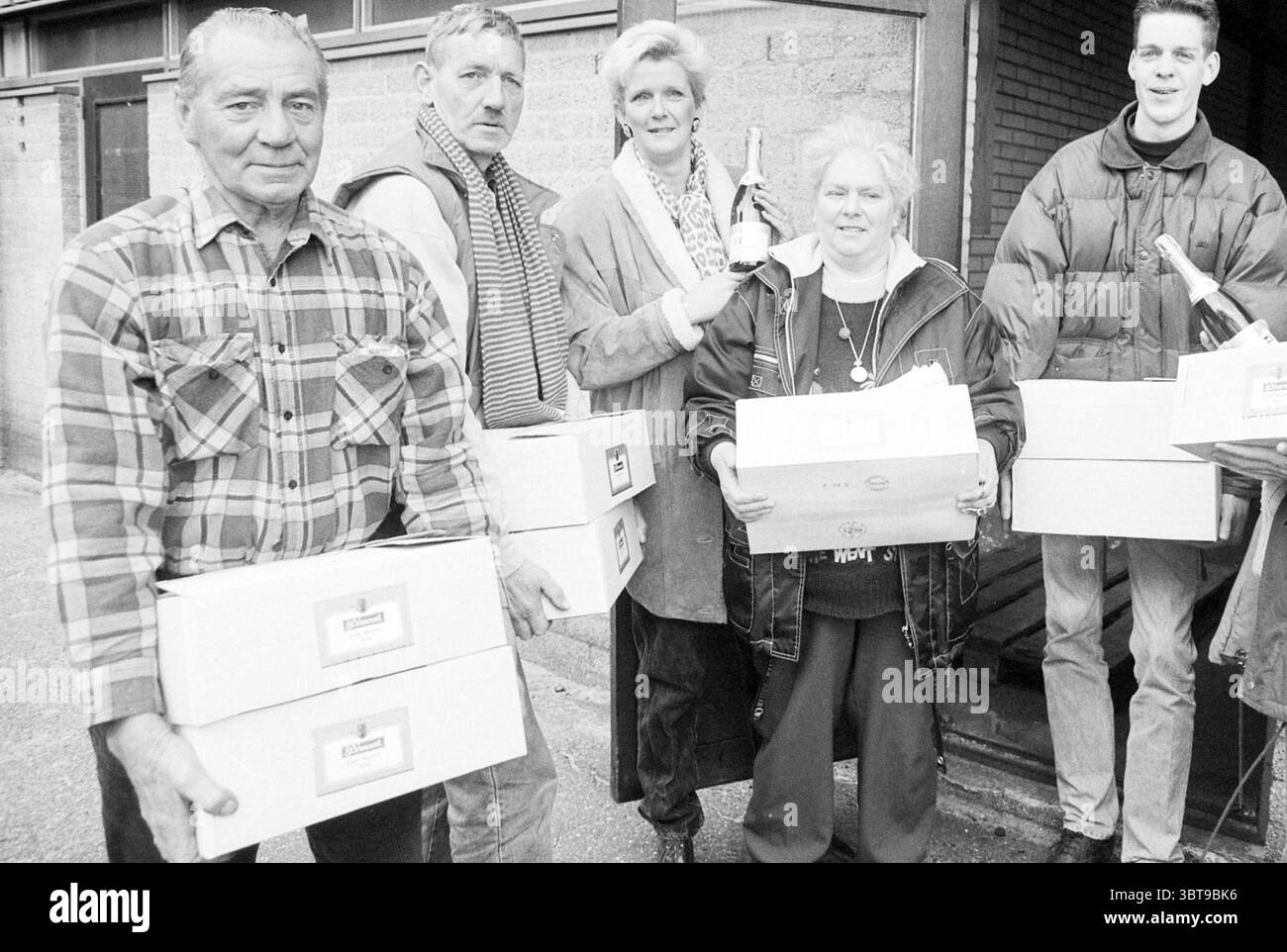 Champagner für neue Abonnenten Haarlem the Netherlands, Whizgle News, Dutch Desk, Niederlande, 1950 - 2000 am 24-11-1995. Diese Themen werden in der Abbildung angezeigt. Die Szene zeigt eine Gruppe von fünf Personen, die zusammen stehen und ein Gefühl von Kameradschaft und Gemeinschaft vermitteln. Die Atmosphäre fühlt sich warm und freundlich an, mit einem Hauch von Feier oder Leistung, die durch die Anwesenheit einer Sektflasche, die von einer Person gehalten wird, suggeriert wird. In Bezug auf die Kleidung zeigen die Personen eine Reihe von lässigen und leicht formellen Kleidungsstücken. Ein Mann auf der linken Seite trägt ein kariertes Hemd unter einer robusten Jacke, was auf eine Praktik hindeutet Stockfoto