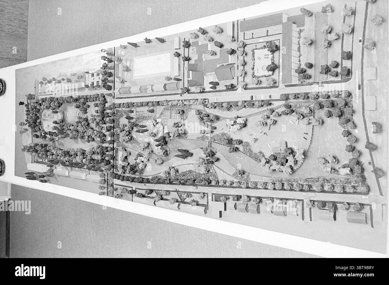 Modellerweiterung Heemskerk. Model, Whizgle News, Dutch Desk, Niederlande, 1950 - 2000 am 03-04-1970. Diese Themen werden in der Abbildung angezeigt. Die Szene zeigt ein detailliertes architektonisches Modell eines Parklayouts, das in Schwarzweiß gerendert wird. Das Modell ist auf einer Ebenen Fläche angeordnet und zeigt eine Vielzahl von Elementen, die ein Gefühl für den beabsichtigten Raum schaffen. Im Vordergrund befinden sich grasbewachsene Flächen, die durch strukturierte Oberflächen dargestellt werden, die auf offene Felder hinweisen. Es gibt Wege, die sich durch das Grün schlängeln und durch glatte, leichtere Abschnitte gekennzeichnet sind, die zu Erkundungen einladen. Verstreut in Miniatur Stockfoto