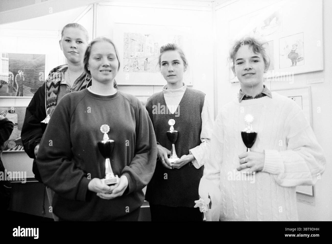 Die Gewinner HABEN DEN Wettbewerb Haarlem the Netherlands, Whizgle News, Dutch Desk, Niederlande, 1950 - 2000 am 04.03.1996. Das Bild enthält diese Themen. In einem gut beleuchteten Innenbereich steht eine Gruppe von vier Personen eng zusammen, zentral zusammengesetzt. Der Hintergrund zeigt helle Kunstwerke an den Wänden, die möglicherweise auf einen Ausstellungsraum hinweisen. Die Motive, alle junge Frauen, zeigen eine Reihe von Ausdrücken, von bescheidenem Lächeln bis zu reflektierenden Blicken. Die erste Person auf der linken Seite trägt eine lange Strickjacke mit Muster über einem dunklen Oberteil, ihre Haare in einem hübschen Brötchen zurückgezogen. Neben ihr, und sowas Stockfoto