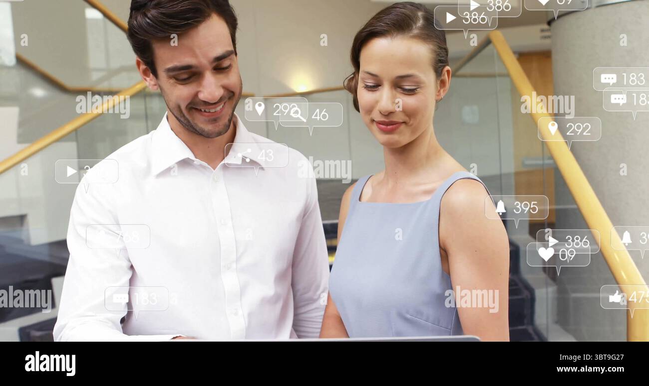 Überprüfung des Laptopbildschirms durch zwei Geschäftskollegen im Treppenhaus des Büros mit Social-Media-Symbolen Stockfoto