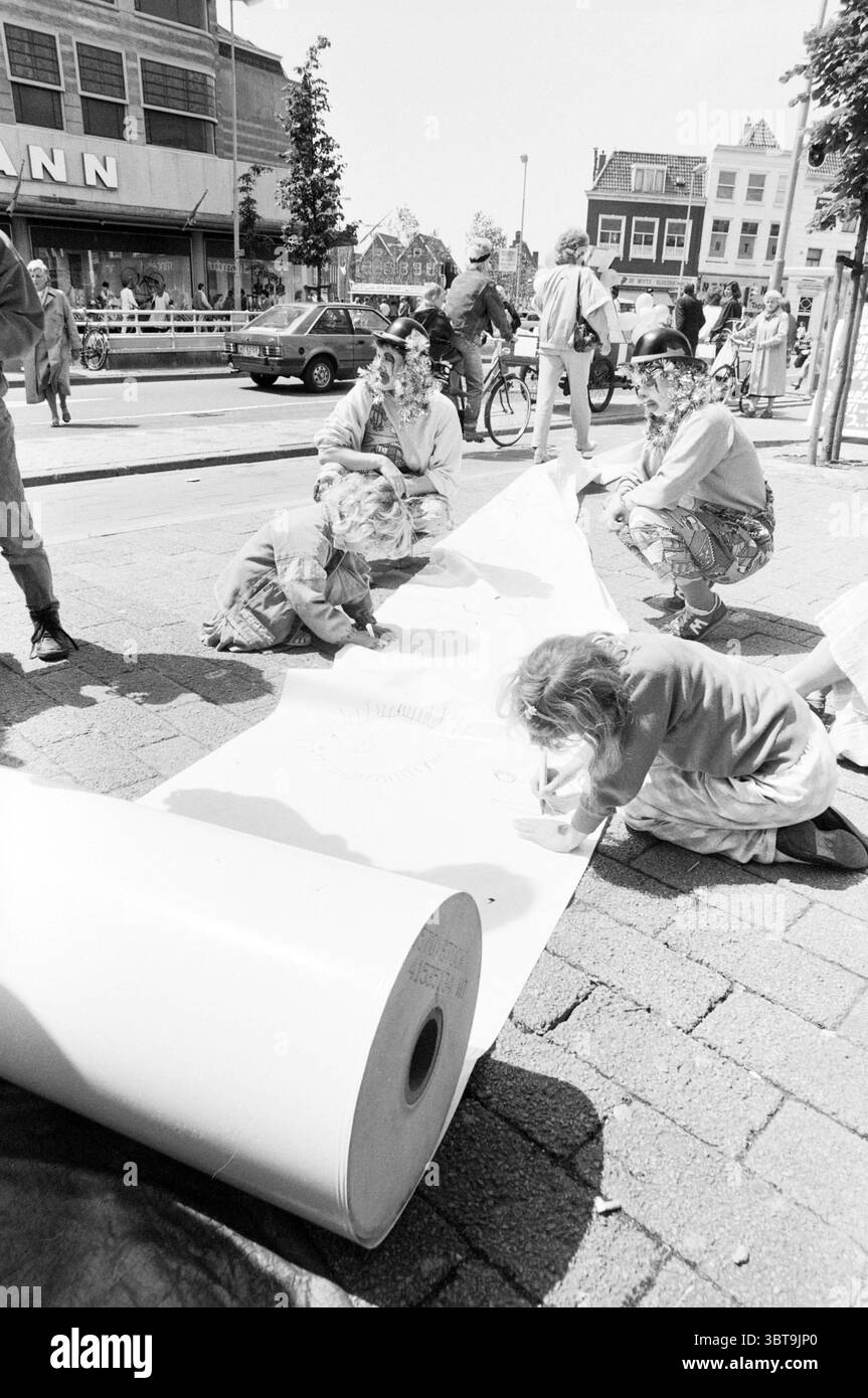 Kinder machen ein riesiges Gedicht auf dem Buttermarkt Gr. Houtstraat Kinder Kinder Kinderheime Kinderparty Kinder Haarlem Grote Houtstraat Niederlande, Whizgle News, Dutch Desk, Niederlande, 1950 - 2000 am 10-06-1987. Diese Themen werden in der Abbildung angezeigt. Die Szene entfaltet sich in einer lebhaften urbanen Umgebung, in der sich mehrere Personen auf einer kopfsteingepflasterten Straße versammeln, die von hellem Tageslicht beleuchtet wird. Die Atmosphäre strahlt ein Gefühl von Gemeinschaft und Kreativität aus. Im Vordergrund sind zwei Kinder gehockt, die sich auf einer großen Rolle weißen Papiers, die entlang des Pavemas entrollt wurde, intensiv färben Stockfoto Kinder machen ein riesiges Gedicht auf dem Buttermarkt Gr. Houtstraat Kinder Kinder Kinderheime Kinderparty Kinder Haarlem Grote Houtstraat Niederlande, Whizgle News, Dutch Desk, Niederlande, 1950 - 2000 am 10-06-1987. Diese Themen werden in der Abbildung angezeigt. Die Szene entfaltet sich in einer lebhaften urbanen Umgebung, in der sich mehrere Personen auf einer kopfsteingepflasterten Straße versammeln, die von hellem Tageslicht beleuchtet wird. Die Atmosphäre strahlt ein Gefühl von Gemeinschaft und Kreativität aus. Im Vordergrund sind zwei Kinder gehockt, die sich auf einer großen Rolle weißen Papiers, die entlang des Pavemas entrollt wurde, intensiv färben Stockfoto