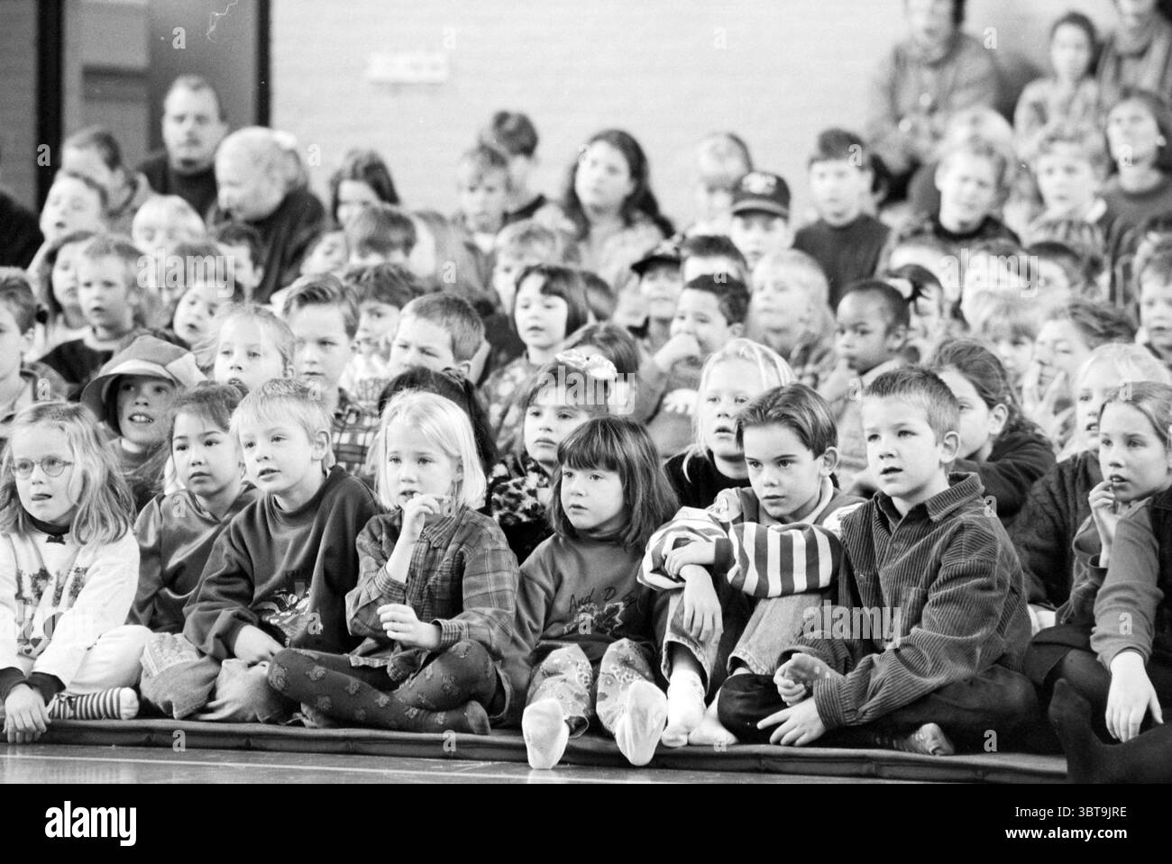 Jenaplanschool H'dorp Hoofddorp the Netherlands, Whizgle News, Dutch Desk, Niederlande, 1950 - 2000 am 22-02-1996. Diese Themen werden in der Abbildung angezeigt. Die Szene zeigt eine große Gruppe von Kindern, die nebeneinander sitzen und sich alle aufmerksam auf etwas vor ihnen konzentrieren. Die Atmosphäre ist spürbar mit einer Mischung aus Neugier und Aufregung. Die Kinder variieren im Alter, wobei eine Reihe von Gesichtsausdrücken ihre Verlobung widerspiegelt; einige sind fasziniert, während andere kontemplativ wirken. Die Frisuren sind vielfältig – einige haben Zöpfe und Locken, andere sind kürzer oder anders gestylt. Das Gerinnsel Stockfoto
