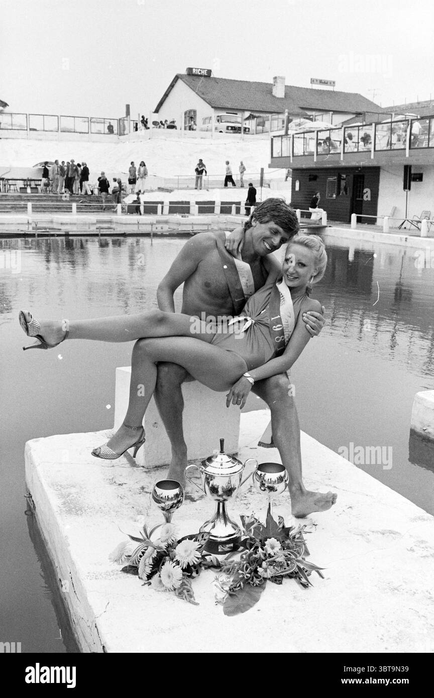 Miss Beach Election Zandvoort II Miss Election Zandvoort Zandvoort, Whizgle News, Dutch Desk, Niederlande, 1950 - 2000 am 08-08-1981. Das Bild enthält diese Themen. In einer ruhigen Szene am Pool sitzt ein jugendliches Paar auf einer erhöhten Plattform über dem Wasser. Der Mann, der nur Badehosen trägt, zeigt ein selbstbewusstes Lächeln, während er sich auf die Frau lehnt, die auf seinem Schoß sitzt. Sie trägt einen stylischen Badeanzug, ergänzt durch High-Heels-Schuhe, und zeigt ein strahlendes Lächeln, was die energiegeladene Atmosphäre der Szene unterstreicht. Um sie herum ist ein großer Pool, seine Oberfläche glatt und r Stockfoto