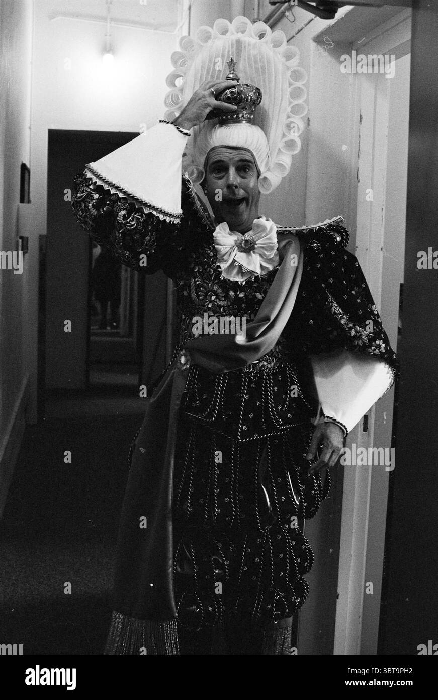 Backstage bei Jos Brink Haarlem, Niederlande, Whizgle News, Dutch Desk, Niederlande, 1950 - 2000 am 12.09.1995. Das Bild enthält diese Themen. Die Szene fängt eine Person in einem auffälligen und ausgeklügelten Kostüm ein und strahlt einen Hauch von Theaterlichkeit aus. Das Outfit ist detailreich und besticht durch raffinierte Verzierungen und eine lebhafte Farbpalette, die von tiefen Tönen dominiert wird, möglicherweise Rot- und Goldtönen, ergänzt durch schimmernde Highlights. Ein großer, reich verzierter Kopfschmuck umrahmt das Gesicht der Person und verziert mit dekorativen Elementen, die sich nach unten bewegen und das extravagante Erscheinungsbild der Figur unterstreichen. Die individu Stockfoto