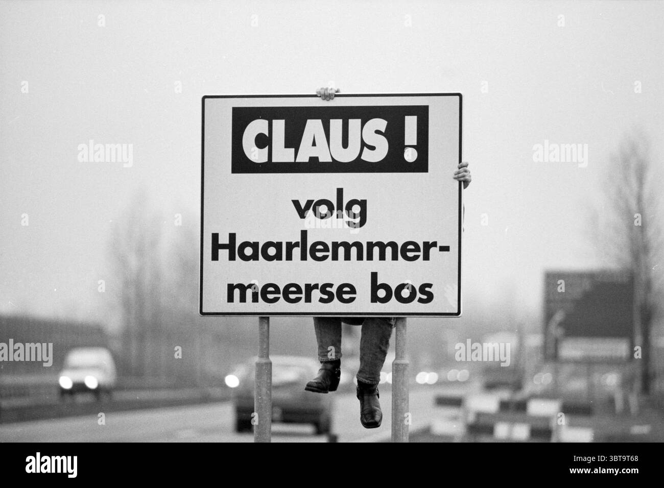 Schild für Claus Bowling in Hoofddorp Hoofddorp Bosweg 19 Niederlande, Whizgle News, Dutch Desk, Niederlande, 1950 - 2000 am 11-02-1992. Diese Themen werden in der Abbildung angezeigt. In einer stummgeschalteten Szene wird eine Figur deutlich sichtbar angezeigt, die ein großes, rechteckiges Zeichen hochhält. Das Schild verfügt über eine auffällige Blockschrift, die sich deutlich vom dezenten Hintergrund abhebt. Die Farben sind eine Kombination aus Schwarz und weiß, was ein Vintage-Gefühl schafft, etwas nostalgisch. Die Abbildung schließt das Schild von hinten, teilweise verdeckt, und unterstreicht so ihre Beziehung zu der Botschaft. Die Einstellung Stockfoto