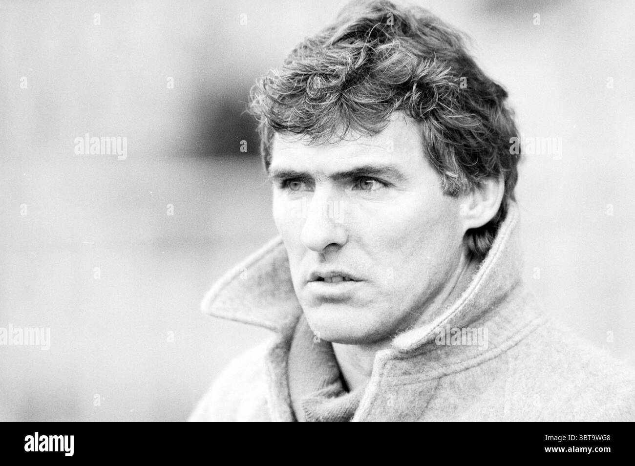 Utrecht - Haarlem + Assistenztrainer van der Lem. Football, Whizgle News, Dutch Desk, Niederlande, 1950 - 2000 am 08-03-1987. Das Bild enthält diese Themen. Die Szene zeigt eine Nahaufnahme eines Individuums mit einem auffälligen Ausdruck. Die Person hat dickes, welliges Haar, das zerzaust wirkt und auf Bewegung oder Aktivität hindeutet. Ihre Gesichtszüge sind definiert und zeigen ein nachdenkliches oder nachdenkliches Verhalten. Die Person trägt einen Mantel mit hohem Kragen, der eine helle Farbe hat und einen Kontrast zu ihrem Teint schafft. Der Hintergrund ist sanft verschwommen, wodurch ein Gefühl von Tiefe entsteht und die Aufmerksamkeit auf die Aufmerksamkeit gerichtet wird Stockfoto