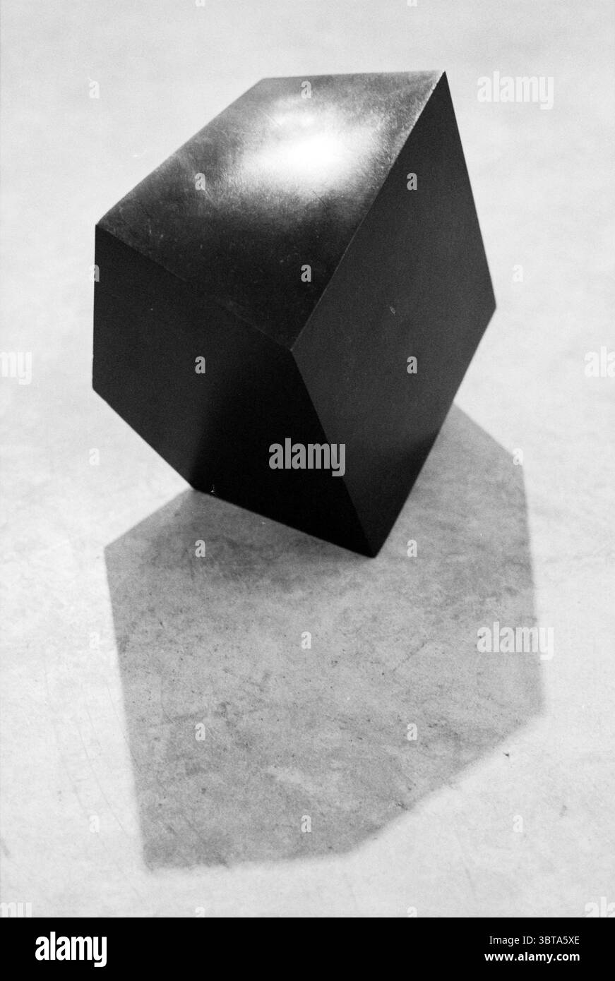 Skulpturengalerie Rumpf Haarlem the Netherlands, Whizgle News, Dutch Desk, Niederlande, 1950 - 2000 am 25-11-1992. Das Bild enthält diese Themen. Die Szene zeigt ein auffälliges schwarzes polyedrisches Objekt, das sich durch seine eckigen Kanten und geometrischen Formen auszeichnet. Die Oberfläche des Objekts ist glatt und glänzend und reflektiert das Licht auf eine Weise, die einen subtilen Glanz erzeugt und seine dreidimensionale Form betont. Der Hintergrund scheint eine strukturierte, helle Oberfläche zu sein, vielleicht ein sanftes Grau oder Beige, die einen scharfen Kontrast zum tiefen Schwarz des Polyeders bildet. Dieser Kontrast lenkt den Blick auf das obj Stockfoto