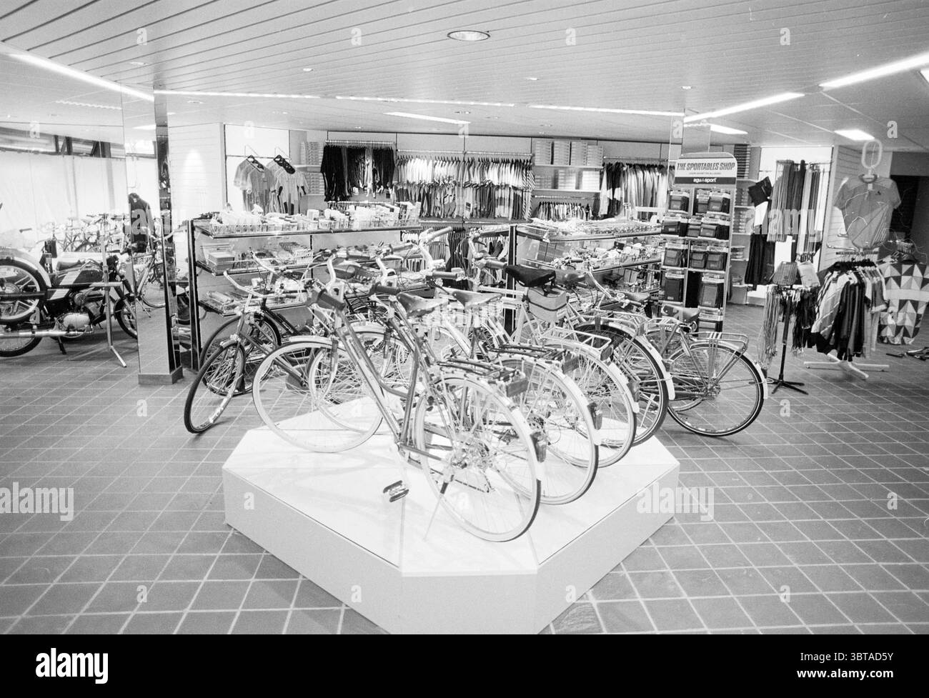 Int. Neuer Fahrradladen Verdonschot Radwege Radfahrer Heemstede Niederlande, Whizgle News, Dutch Desk, Niederlande, 1950 - 2000 am 27-02-1989. Diese Themen werden in der Abbildung angezeigt. In einem geräumigen Einzelhandelsbereich steht ein kreisförmiges Display mit mehreren Fahrrädern im Mittelpunkt, die optisch ansprechend angeordnet sind. Die Fahrräder haben ein schlankes Design, das eine klare und moderne Ästhetik aufgreift. Ihre Rahmen sind in einer Vielzahl von Farben lackiert, überwiegend in Silber- und Schwarztönen, mit Akzenten in helleren Tönen, die dem Display Lebendigkeit verleihen. Um das Fahrraddisplay herum Stockfoto