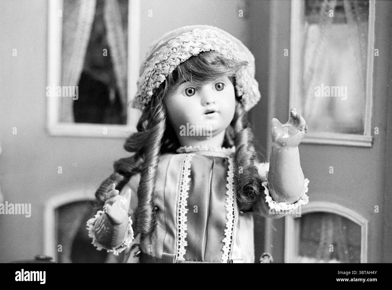 Marionettenmuseum Amstelveen Museum Museen Puppen Puppenspiele Puppenspiele Puppentheater Amstelveen, Whizgle News, Dutch Desk, Niederlande, 1950 - 2000 am 20-11-1979. Dies sind die Themen im Bild. Die Szene zeigt eine Vintage-Puppe mit einem zarten und lebensechten Aussehen. Sie hat langes, welliges Haar, das über ihre Schultern fällt, eingerahmt von einer weichen, hellen Mütze mit einem dezenten Blumenmuster. Ihr Gesicht ist porzellanartig, mit hellen, ausdrucksstarken Augen und einem leicht offenen Mund, was ein Gefühl von Unschuld und Neugier weckt. Die Puppe trägt ein charmantes Outfit, das sich durch auszeichnet Stockfoto