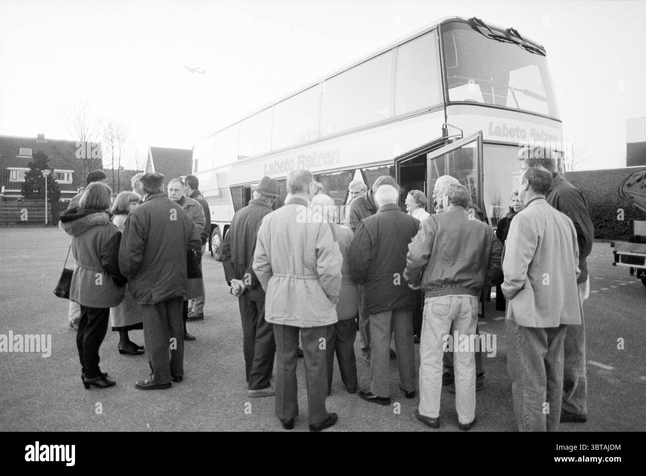 Abfahrtsbus nach den Haag, Whizgle News, Dutch Desk, Niederlande, 1950 - 2000 am 16-02-1994. Dies sind die Elemente im Bild. Die Szene zeigt eine Gruppe von Einzelpersonen, die sich in ungezwungener, aber organisierter Weise um einen großen, zweistöckigen Bus versammelt haben. Das vielfältige Publikum besteht aus Männern und Frauen, die jeweils in einer Reihe von Oberbekleidung gekleidet sind, die ein kühles oder mildes Klima anzeigt, wobei viele Mäntel und Jacken in gedämpften Tönen wie Grau, Braun und Blau tragen. Die Menschen wirken engagiert und animiert, einige neigen sich eng zu Gesprächen, während andere etwas auseinander stehen, lächeln oder schauen Stockfoto