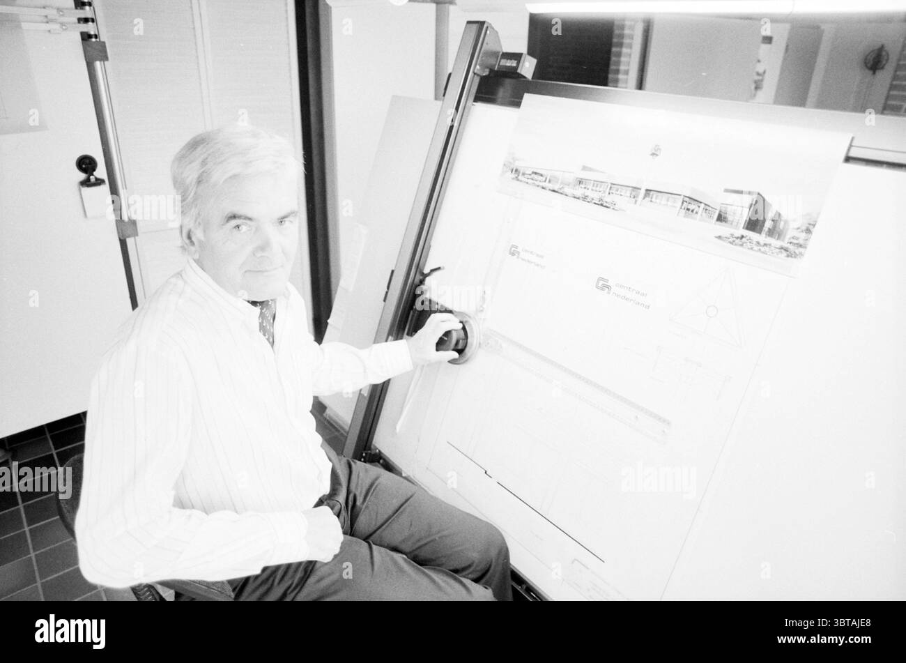 Architekt Tromp Aalsmeer Persons Aalsmeer, Whizgle News, Dutch Desk, Niederlande, 1950 - 2000 am 11-05-1989. Diese Themen werden in der Abbildung angezeigt. Die Szene erfasst eine Person, die an einem Zeichnungstisch sitzt, und schlägt einen Arbeitsbereich vor, der sich auf Design oder Architektur konzentriert. Die Person trägt ein helles gestreiftes Hemd und eine gemusterte Krawatte, die ein professionelles Aussehen vermittelt. Ihr Ausdruck wirkt kontemplativ oder konzentriert und deutet auf die emotionale Bindung an ihre Arbeit hin. Die Zeichnungstabelle zeigt einen teilweise angezeigten Plan oder einen Plan mit Linien und Formen, die detaillierte Architekturarbeiten erfordern. Th Stockfoto