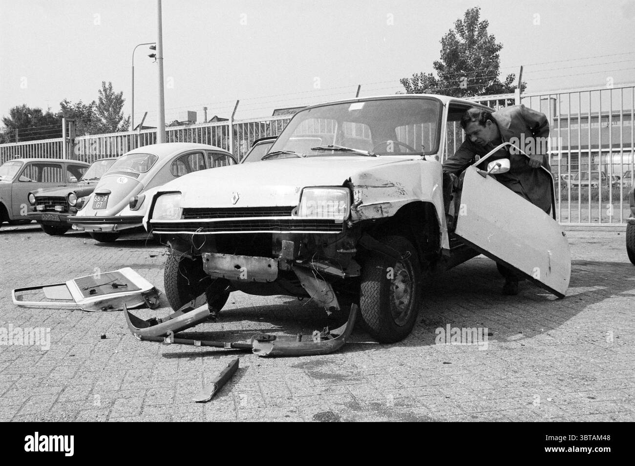 Inspektionswagendepot Haarlem Police Police Police Haarlem Niederlande, Whizgle News, Dutch Desk, Niederlande, 1950 - 2000 am 09-07-1984. Dies sind die Themen im Bild. Die Szene zeigt einen Oldtimer, der besonders abgenutzt und beschädigt ist und auf einem griffigen, gepflasterten Untergrund geparkt ist. Sein Körper ist in erster Linie ein verblichenes weiß, das von Rost und Dellen getrübt ist, was ein Gefühl der Vernachlässigung hervorruft. Der vordere Stoßfänger ist teilweise abgenommen und die Scheinwerfer sind gedämpft, was zu seinem verwaisten Aussehen beiträgt. In der Nähe befindet sich ein weiterer Oldtimer mit abgerundeter Form und markanter Silhouette in einem etwas dunkleren Ton, möglicherweise in einem Mu Stockfoto