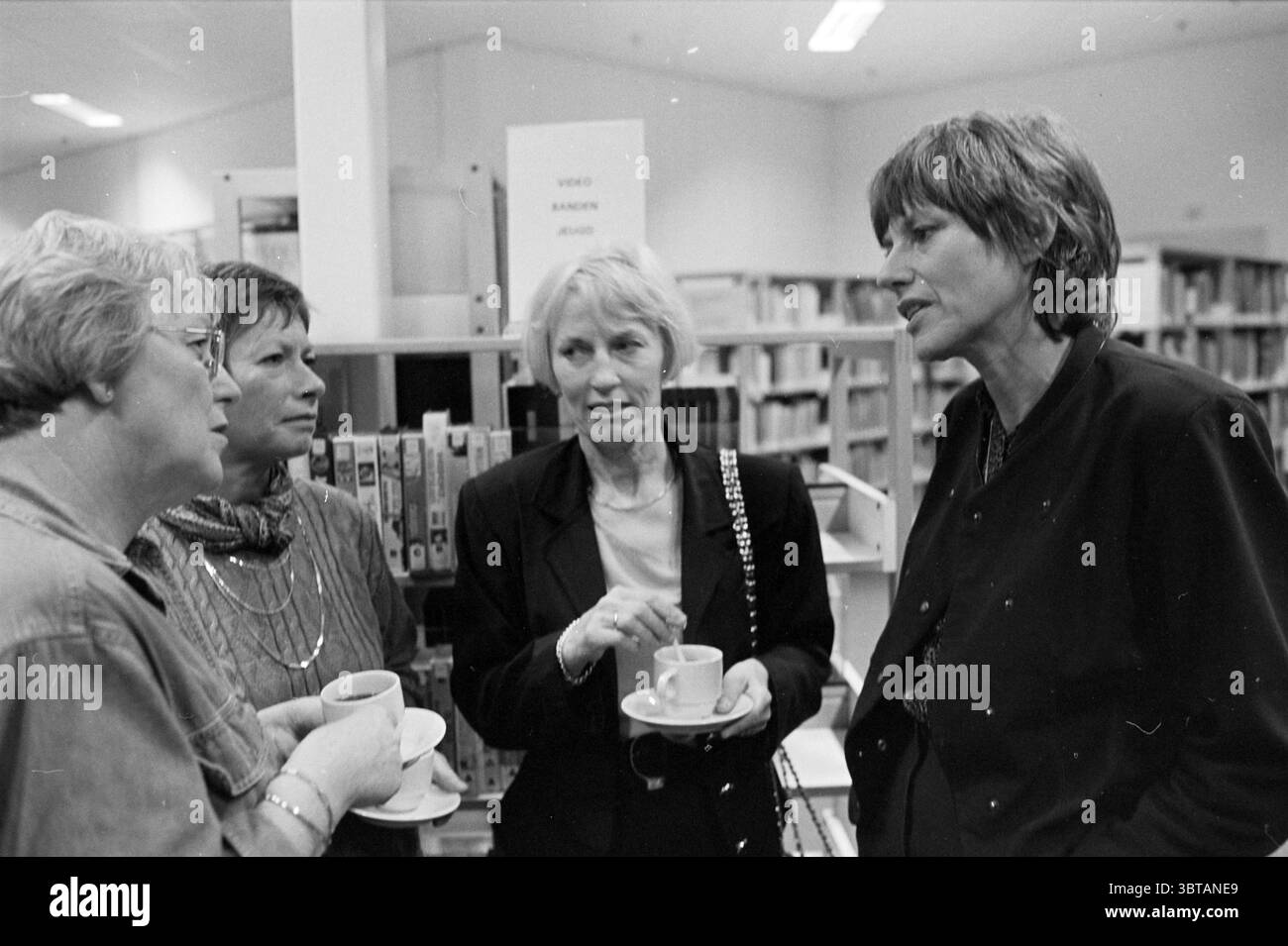 Schriftstellerin Annette Heffels Bibliothek IJmuiden IJmuiden the Netherlands, Whizgle News, Dutch Desk, Niederlande, 1950 - 2000 am 12-11-1995. Dies sind die Elemente im Bild. In einem gemütlichen Innenbereich führen vier Frauen ein lebhaftes Gespräch. Der Hintergrund ist mit gut organisierten Bücherregalen gefüllt, die eine Bibliothek oder eine ähnliche Umgebung vorschlagen. Die allgemeine Stimmung ist warm und intim, verstärkt durch sanfte, indirekte Beleuchtung, die eine sanfte Atmosphäre schafft. Die Frauen zeigen eine Reihe von Ausdrücken, von nachdenklich bis animiert. Sie tragen legere, aber stilvolle Kleidung in verschiedenen Farben Stockfoto