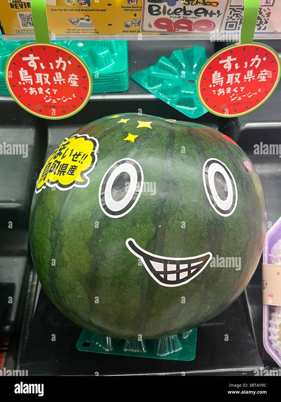 Vertikale Aussicht, riesige, frische Wassermelone mit einem Lächeln und süßem Gesicht. Don Don Donki, Singapur. Direkter Import aus Japan, Präfekturen Tottori. - Smartphone-aufgenommenes Stockfoto
