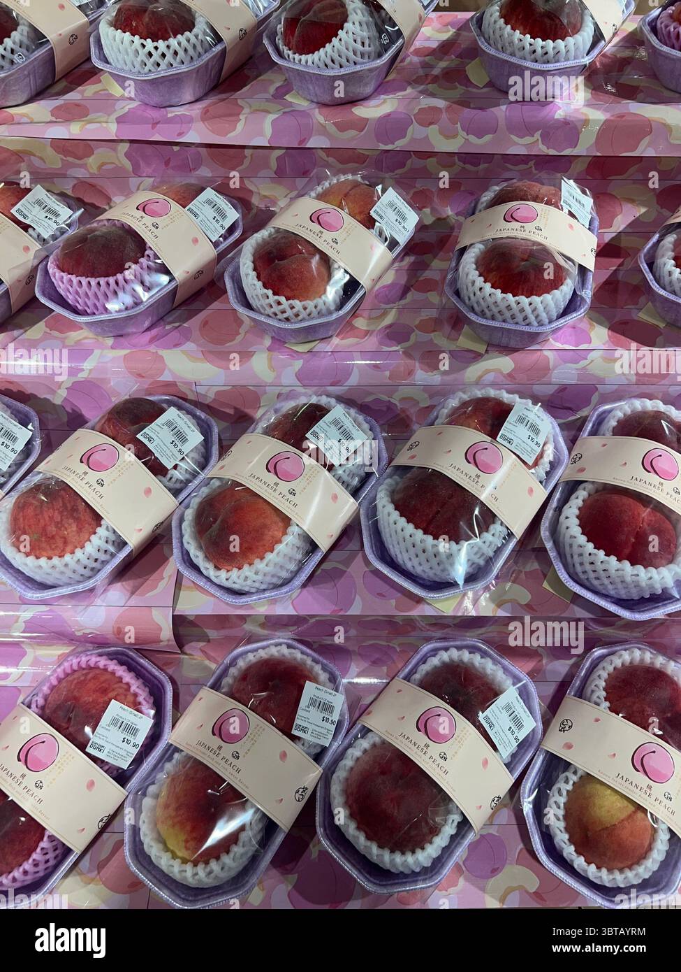 Vertikale Ansicht, Pfirsiche Verpackung bei Don Don Donki, Singapur. Obst wird direkt aus Japan importiert und wird für den Verkauf ins Ausland verkauft. Preisetikett oben. Dichte Abdichtung. - Smartphone-aufgenommenes Stockfoto