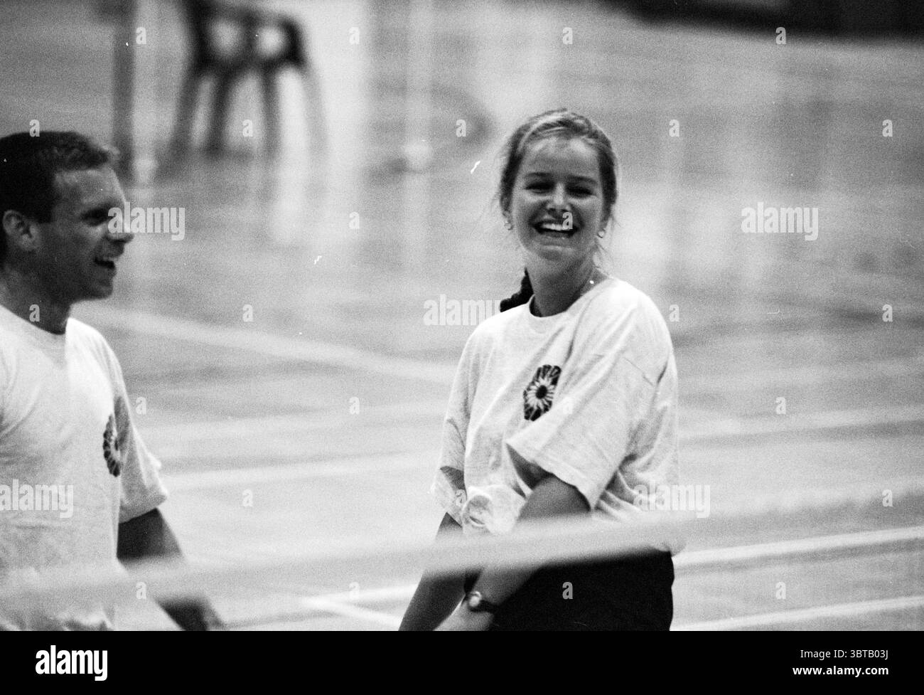 Badminton Let it be Champion Haarlem the Netherlands, Whizgle News, Dutch Desk, Niederlande, 1950 - 2000 am 20.01.1996. Das Bild enthält diese Themen. In einem geräumigen Indoor Gymnasium strahlt der polierte Holzboden unter den hellen Deckenleuchten und strahlt ein warmes Licht in der Umgebung aus. Zwei Menschen sind in einem Moment des Lachens gefangen und tragen zu einer Atmosphäre voller Energie und Kameradschaft bei. Eine Person, ein Mann, trägt ein schlichtes weißes T-Shirt, das sich von den warmen Farbtönen der Holzoberfläche abhebt. Er steht ein wenig Abstand zum anderen, sein Ausdruck ist animiert, mit Stockfoto