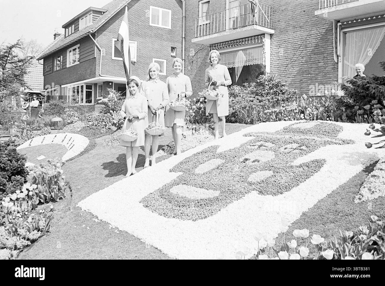 Blumenmädchen in Volendam Blumen und Blumenmädchen, Whizgle News, Dutch Desk, Niederlande, 1950 - 2000 auf 27-04-1968. Diese Themen werden in der Abbildung angezeigt. In einem bezaubernden Garten stehen vier Frauen zusammen, jede trägt elegante, helle Kleider, die ein Gefühl von Einheit und Stil ausstrahlen. Ihre Ausdrücke sind hell und einladend, was zu einer insgesamt fröhlichen Atmosphäre beiträgt. Jede Frau hält einen kleinen Korb mit Blumen, der die festliche Stimmung der Szene unterstreicht. Der Garten selbst ist akribisch angelegt, mit einer bunten Auswahl an Blumen und Pflanzen, die einen andeuten Stockfoto