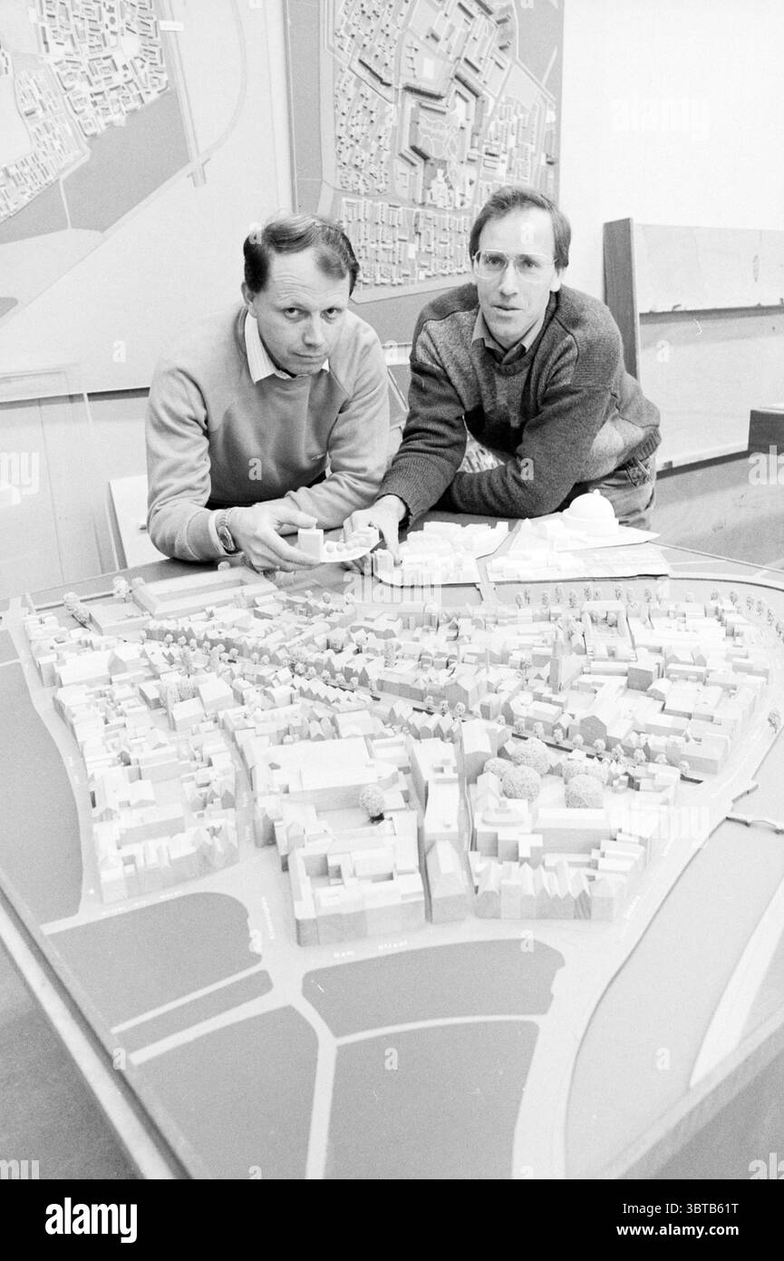 Public Works Department Model Construction - 2 Models Model, Whizgle News, Dutch Desk, Niederlande, 1950 - 2000 am 16-03-1986. Diese Themen sind in der Abbildung dargestellt. Die Szene zeigt zwei Personen, die im Vordergrund stehen und sich über ein detailliertes Architekturmodell lehnen. Sie wirken engagiert und fokussiert und untersuchen die Feinheiten des Layouts vor ihnen. Das Modell selbst ist eine komplizierte Darstellung einer Stadt oder eines städtischen Gebiets und zeigt verschiedene Gebäude, Grünflächen und Straßen, die alle in einer gedämpften Farbpalette von weiß, Grau und Beige präsentiert werden, wodurch es sauber und professionell ist Stockfoto