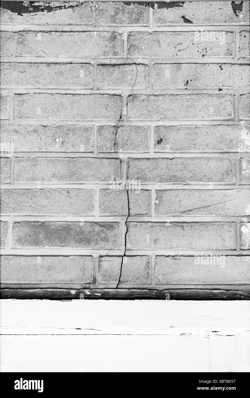 Panden de Koog Texel (aann.mij NRD-Holl.) Buildings, Whizgle News, Dutch Desk, Niederlande, 1950 - 2000 am 27-12-1978. Dies sind die Elemente im Bild. Die Szene zeigt eine strukturierte Wand aus rechteckigen Ziegeln, die in einem klassischen Muster angeordnet sind. Die Steine zeigen eine gedämpfte Palette von Grautönen mit Farbvariationen, die darauf hindeuten, dass einige verwittert oder abgenutzt sind. Ein wahrnehmbarer Riss verläuft vertikal durch die Oberfläche, wodurch eine gezackte Linie entsteht, die die Gleichmäßigkeit des Mauerwerks unterbricht. Der Mörtel zwischen den Ziegeln weist Alterserscheinungen auf, wobei einige Bereiche dunkler oder erodiert erscheinen, was zu dem hinzu kommt Stockfoto