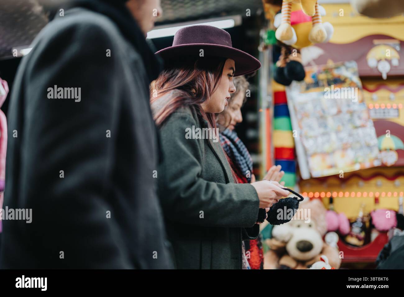 Frau mit Hut erkundet den pulsierenden Wintermarkt mit Freunden Stockfoto