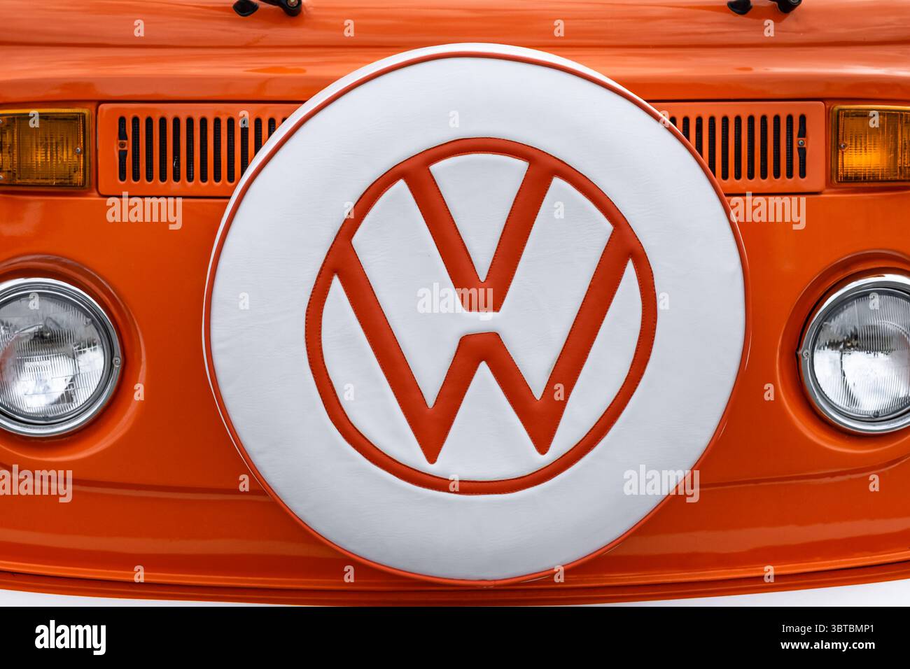 VW-Symbol in der Mitte der Motorhaube des Retro-Busses. Nahaufnahme Vorderansicht des VW T2 Campervan Classic in Orange und weiß. Vintage Volkswagen Transporter. Tr Stockfoto