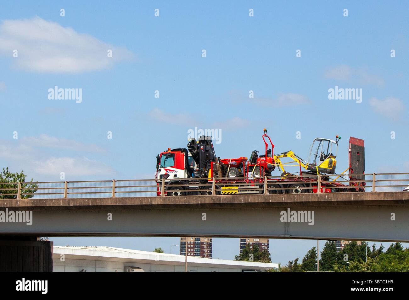 Ein Lastkraftwagen von Speedy Services transportiert Baumaschinen auf einem Tieflader-Anhänger auf der Umgehungsstraße A5 in Tamworth, Staffordshire. Stockfoto