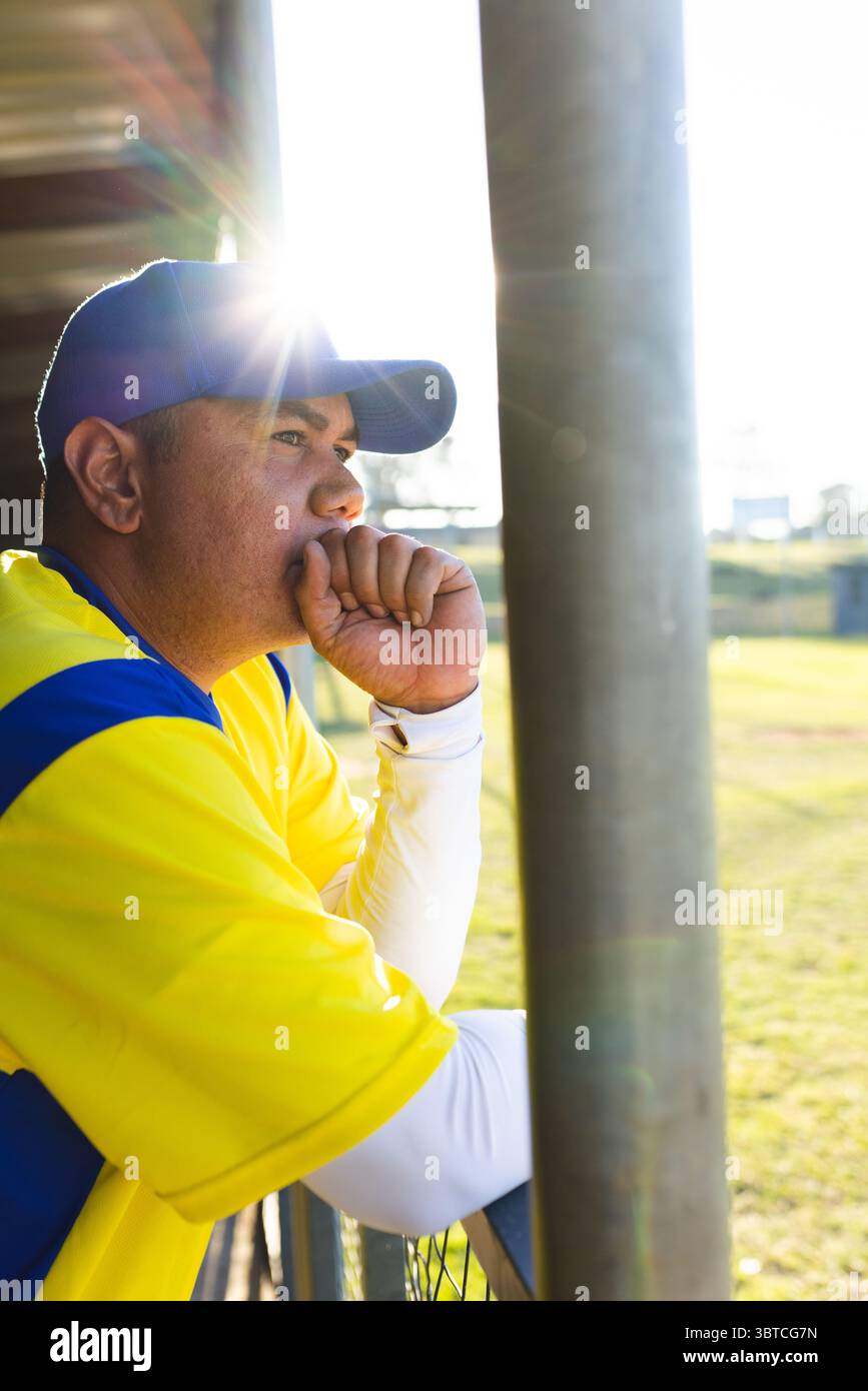 Sitzt in einer Ausgrabung am Maschendrahtzaun, hispanischer Mann in gelbem Jersey, blauer Mütze, Kopierraum Stockfoto