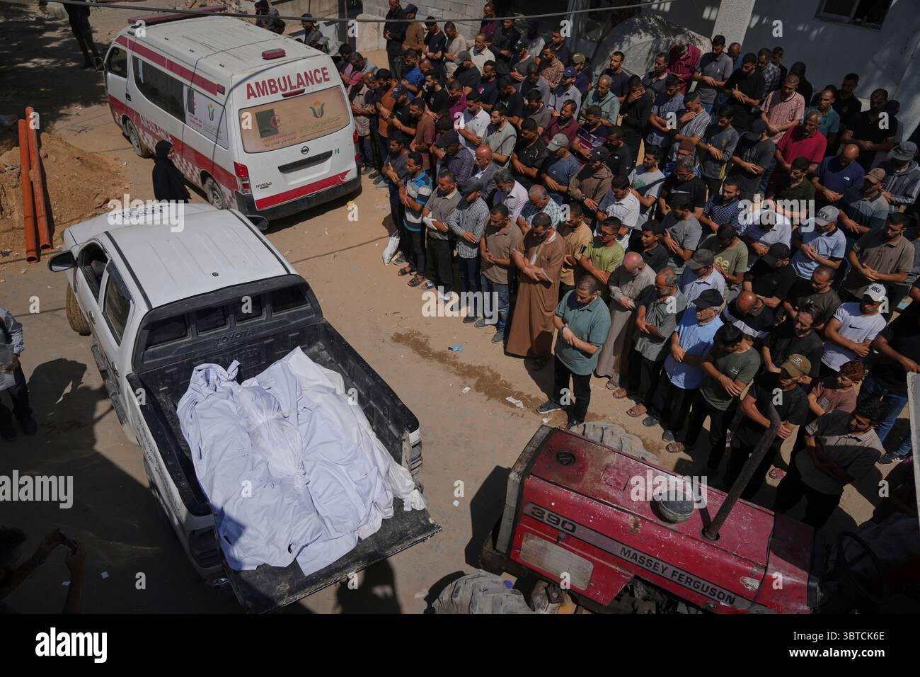 Mourners pray beside the bodies of Palestinians who were killed by an Israeli airstrike, during their funeral at Shifa Hospital in Gaza City Tuesday, July 15, 2025. (AP Photo/Jehad Alshrafi) Stockfoto