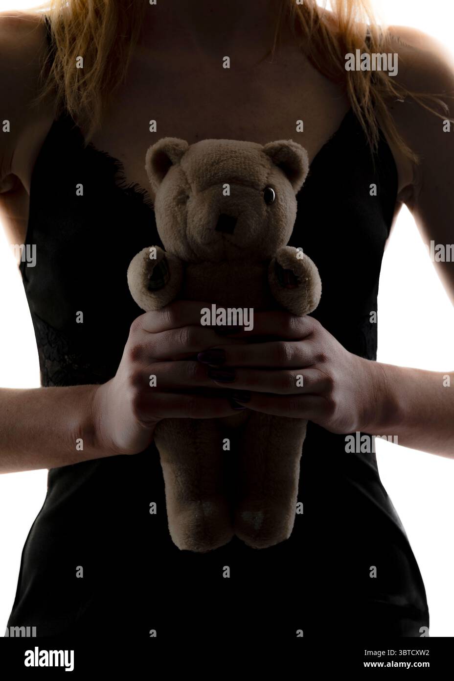 Eine Frau in einem schwarzen Kleid hält einen Teddybären. Stockfoto