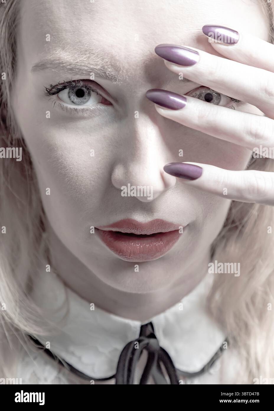 Eine Frau mit heller Haut und blonden Haaren bedeckt ihr Gesicht teilweise mit der Hand und zeigt ein Auge. Ihre Lippen sind leicht geteilt und sie ist müde Stockfoto Eine Frau mit heller Haut und blonden Haaren bedeckt ihr Gesicht teilweise mit der Hand und zeigt ein Auge. Ihre Lippen sind leicht geteilt und sie ist müde Stockfoto