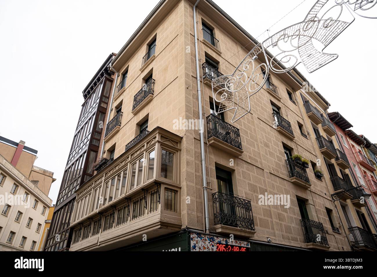 Besucher bewundern das einzigartige Design eines historischen Gebäudes in Pamplona, Navarra, umgeben von Feiertagsdekorationen, die den Geist des Feierns verkörpern Stockfoto