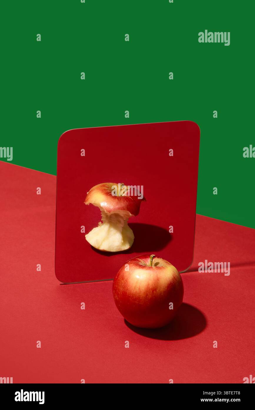 Apfel, der in den Spiegel blickt, sieht den gegessen Kern anstelle von ganzen Früchten Stockfoto