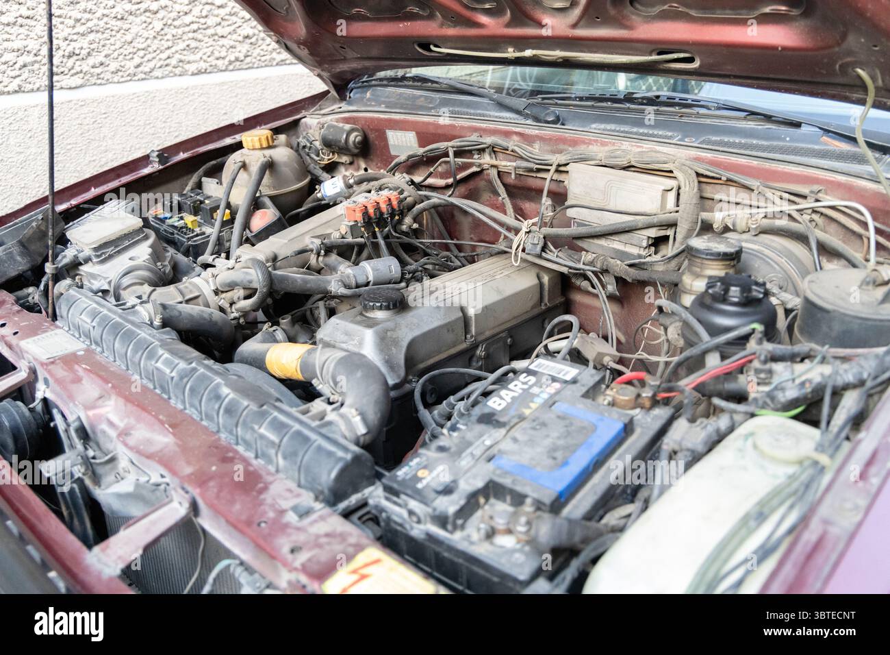 Nahaufnahme eines Oldtimers mit geöffneter Motorhaube. Konzept der Fahrzeugreparatur, Wartung und mechanischen Probleme. Stockfoto