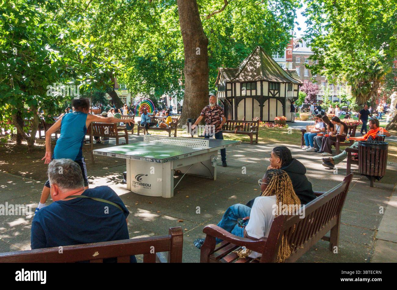 Die Leute spielen Tischtennis und entspannen sich im Sommer auf dem Soho Square im Zentrum von London Stockfoto