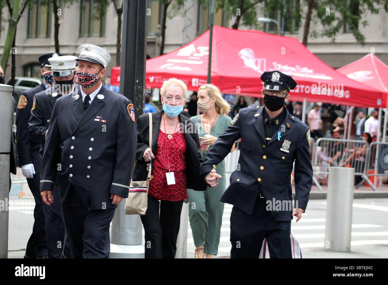 10. September 2020, New York, New York, USA: In einem beispiellosen Kontext aufgrund von COVID-19 war das Gedenken an die Anschläge von 9/11 in New York anders. Ein junger Polizist der NYPD hält die Hand einer älteren Frau, bevor er zum Beispiel die Feuerwehrleute in das Gedenkgelände betritt, um einem geliebten Menschen Tribut zu zollen. Die Hinterbliebenen sahen sich auch mit dem damaligen Präsidentenkontext konfrontiert, als Joe Biden, demokratischer Präsidentschaftskandidat, gefolgt von Vizepräsident Mike Pence während der Zeremonie, stattfand. Zum ersten Mal seit 19 Jahren, seit Al-Qaida-Aktivisten den World Trade C zerstörten Stockfoto